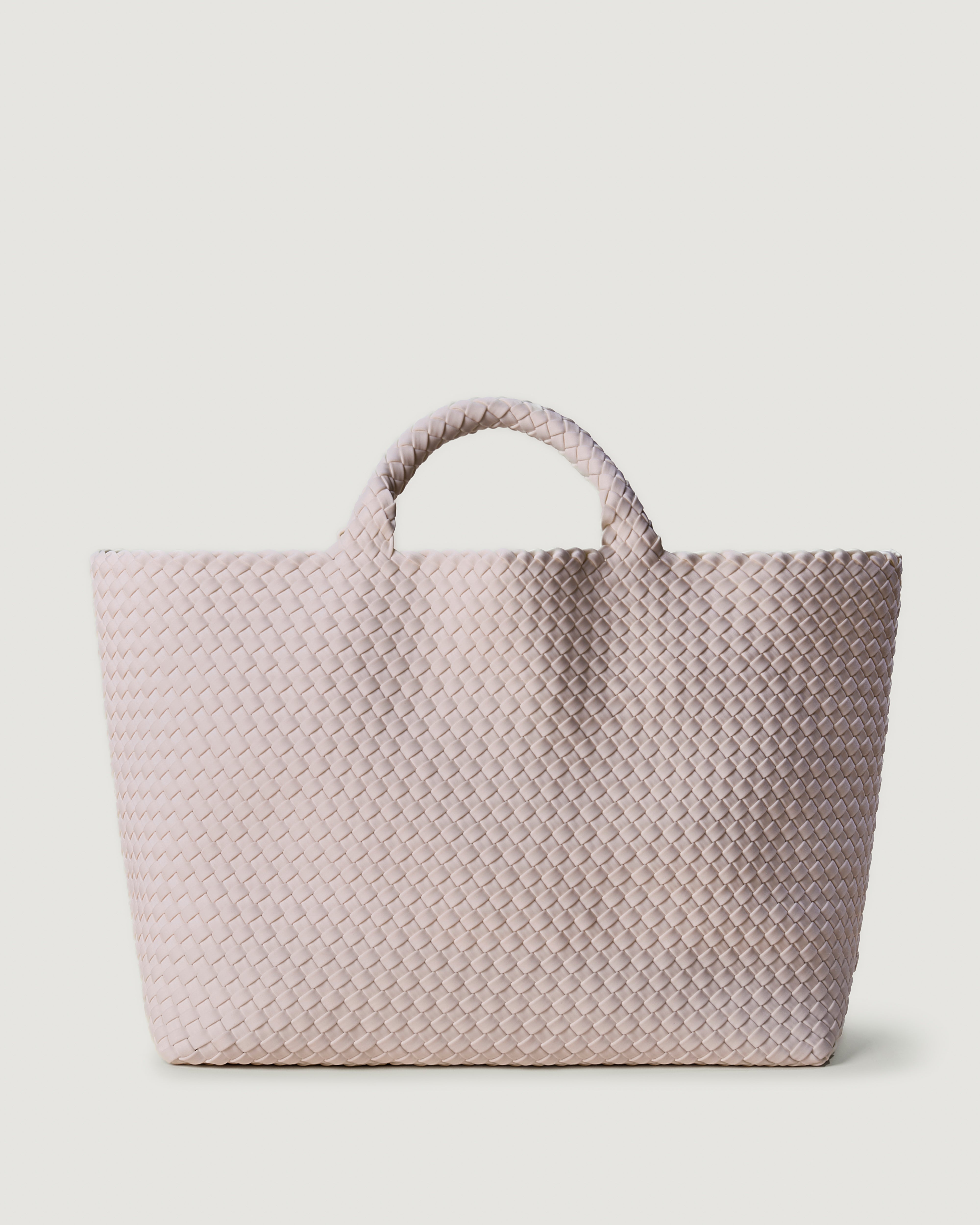St. Barths Tote in Petal, handwoven in petal pink neoprene. Featuring an open top, and woven top handles.