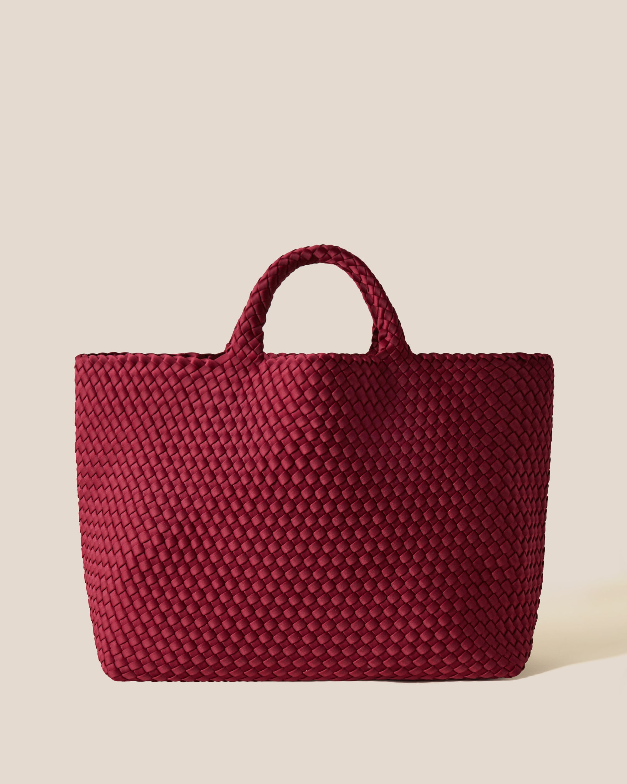 St. Barths Tote in Rosewood, a burgundy tone, in handwoven neoprene, featuring an open top, and woven top handles.