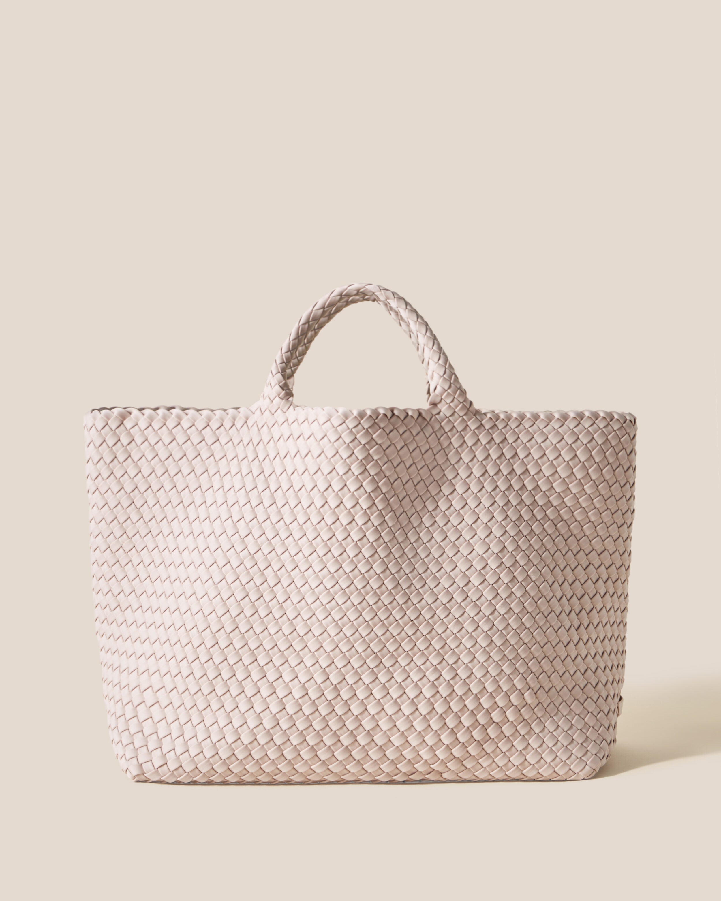 St. Barths Tote in Shell Pink, a soft ballet pink tone, in handwoven neoprene, featuring an open top, and woven top handles.