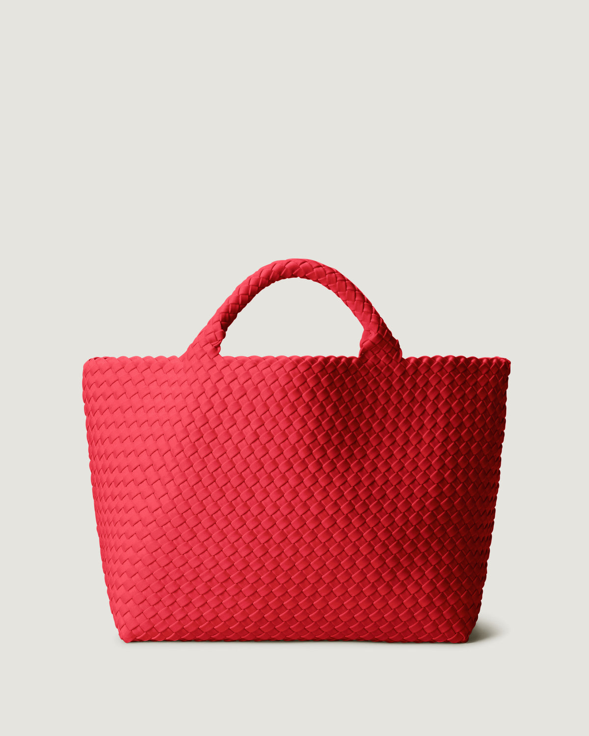 St. Barths Tote in Ink Cerise, a bright cherry red tone, in handwoven neoprene, featuring an magnetic closure, and woven top handles.