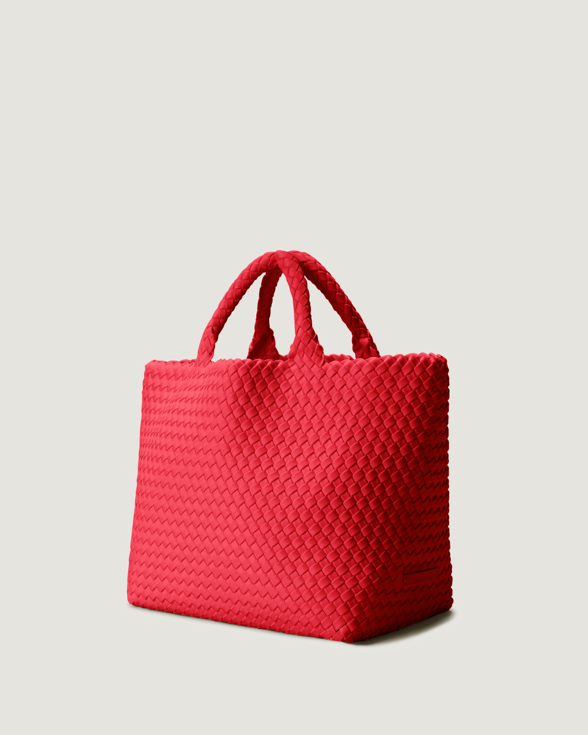 St Barths Tote in Cerise shown from a side angle, highlighting its handwoven neoprene construction and open top with magnetic snap closure.