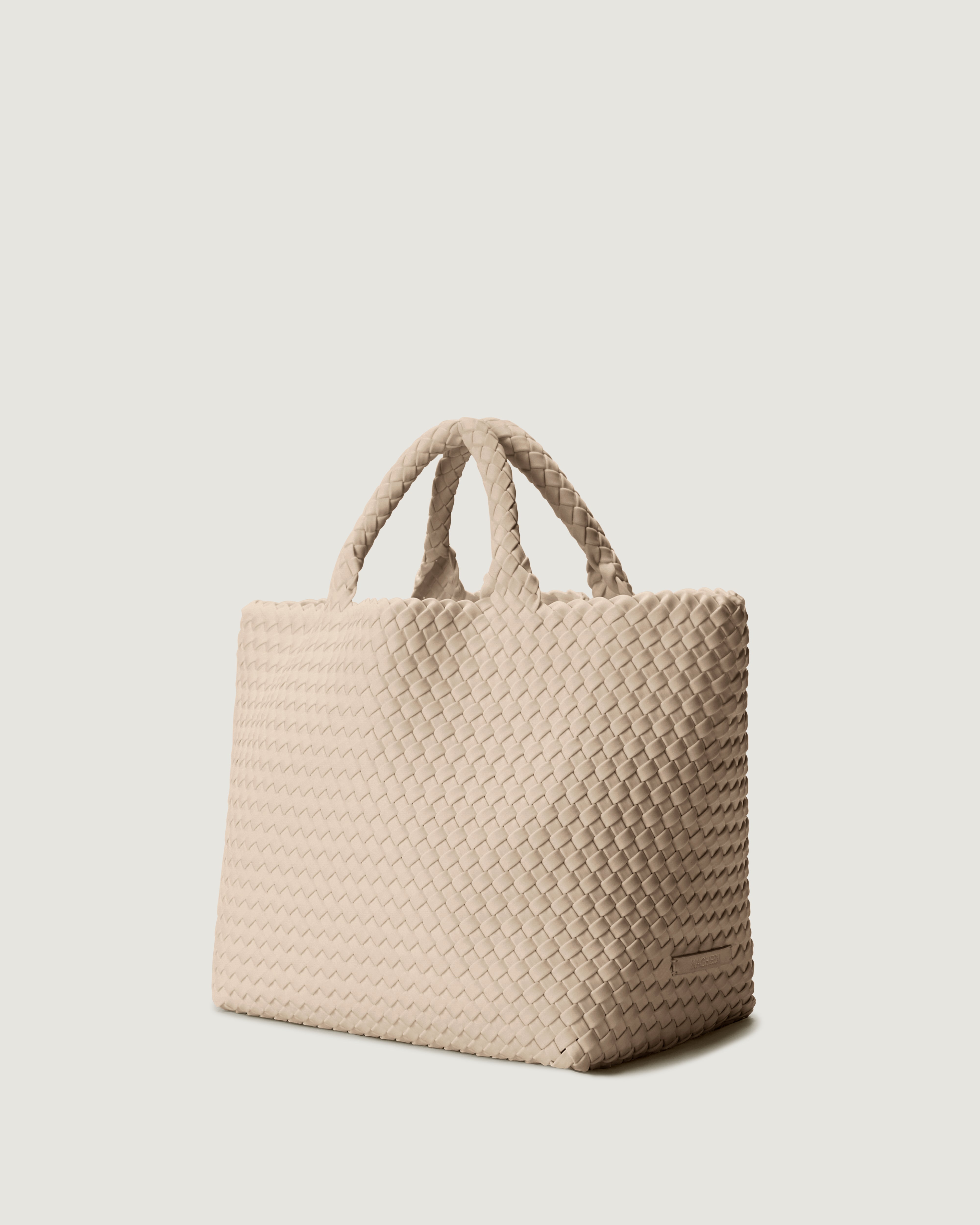 St. Barths Tote in Ecru shown from a side angle, highlighting its handwoven neoprene construction and open top.