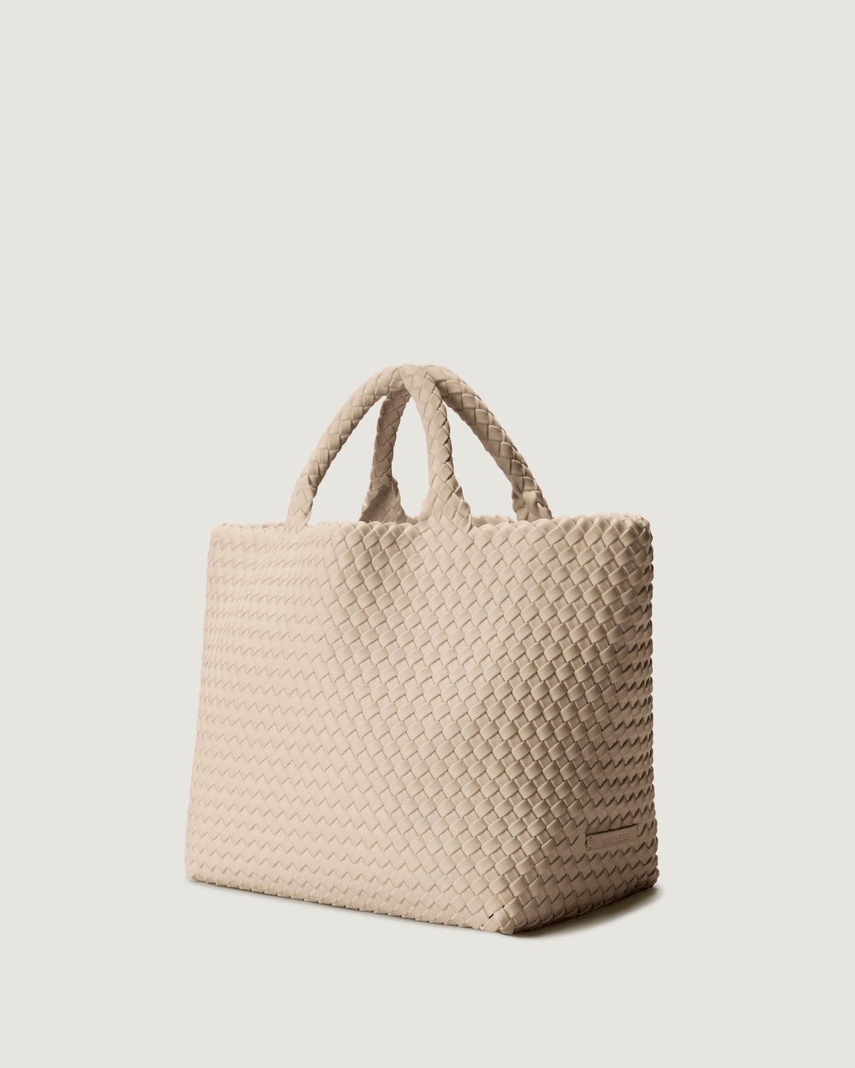 St Barths Tote in Ecru shown from a side angle, highlighting its handwoven neoprene construction and open top with magnetic snap closure.