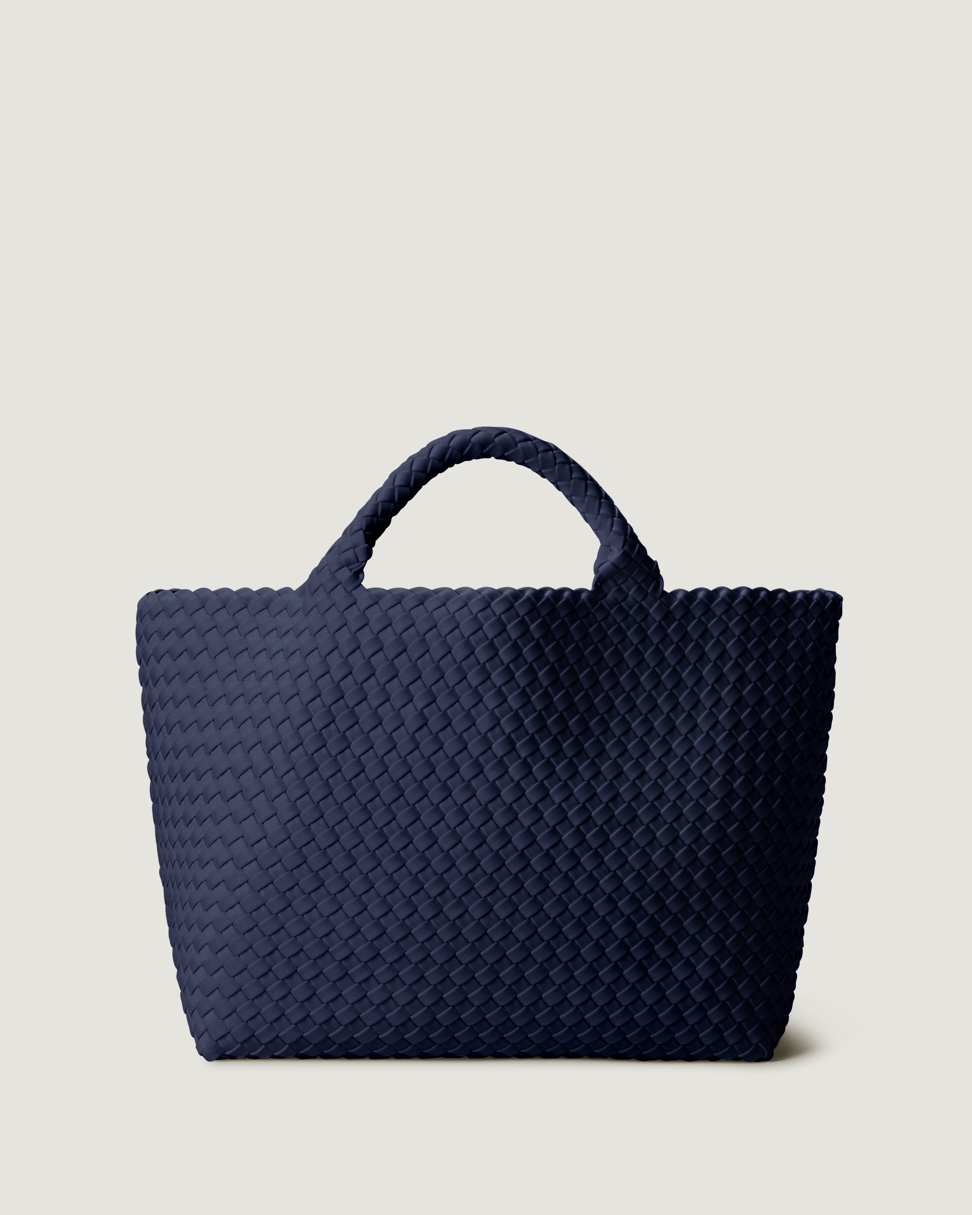 St. Barths Tote in Ink Blue, a navy blue tone, in handwoven neoprene, featuring an open top, magnetic closure, and woven top handles.