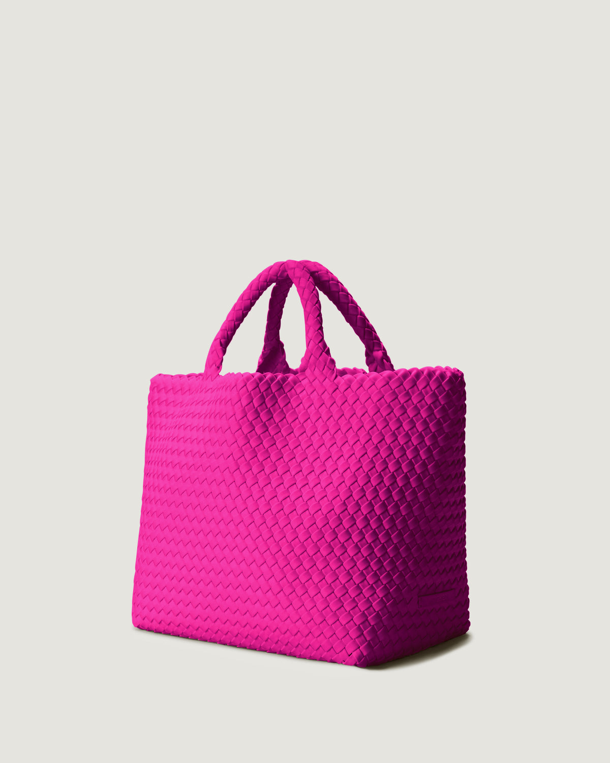 St Barths Tote in Miami Pink shown from a side angle, highlighting its handwoven neoprene construction and open top with magnetic snap closure.