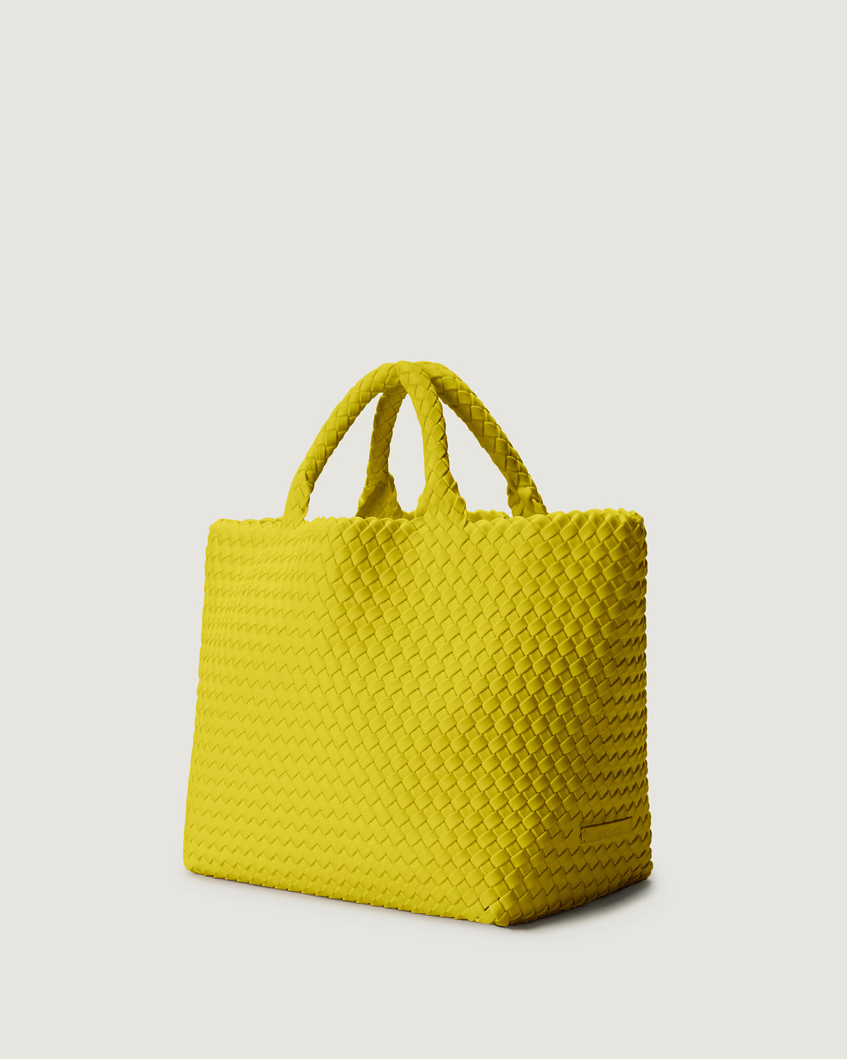 St Barths Tote in Ochre shown from a side angle, highlighting its handwoven neoprene construction and open top with magnetic snap closure.