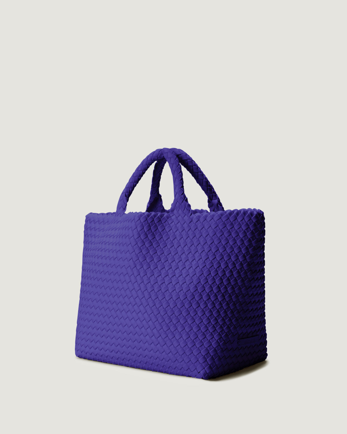 St Barths Tote in Ultramarine shown from a side angle, highlighting its handwoven neoprene construction and open top with magnetic snap closure.