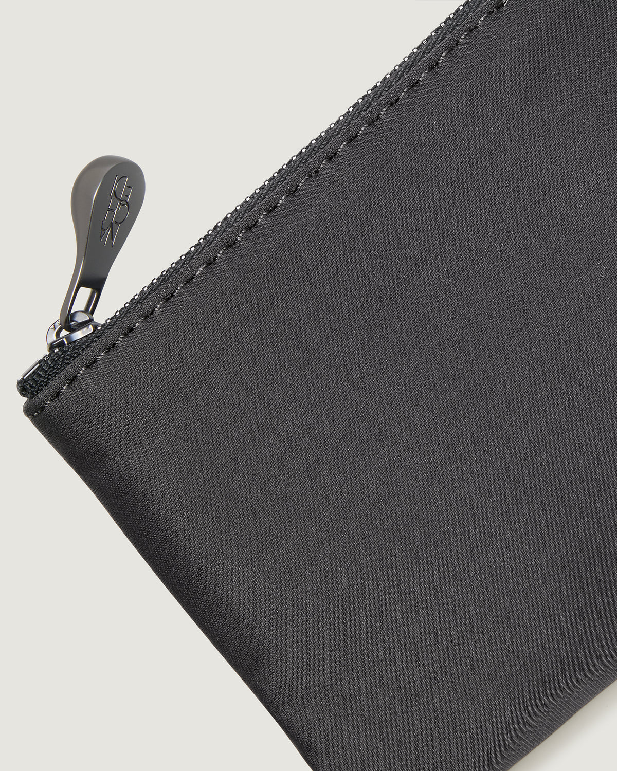 Close-up of an ash gray nylon pouch with a silver zipper pull
