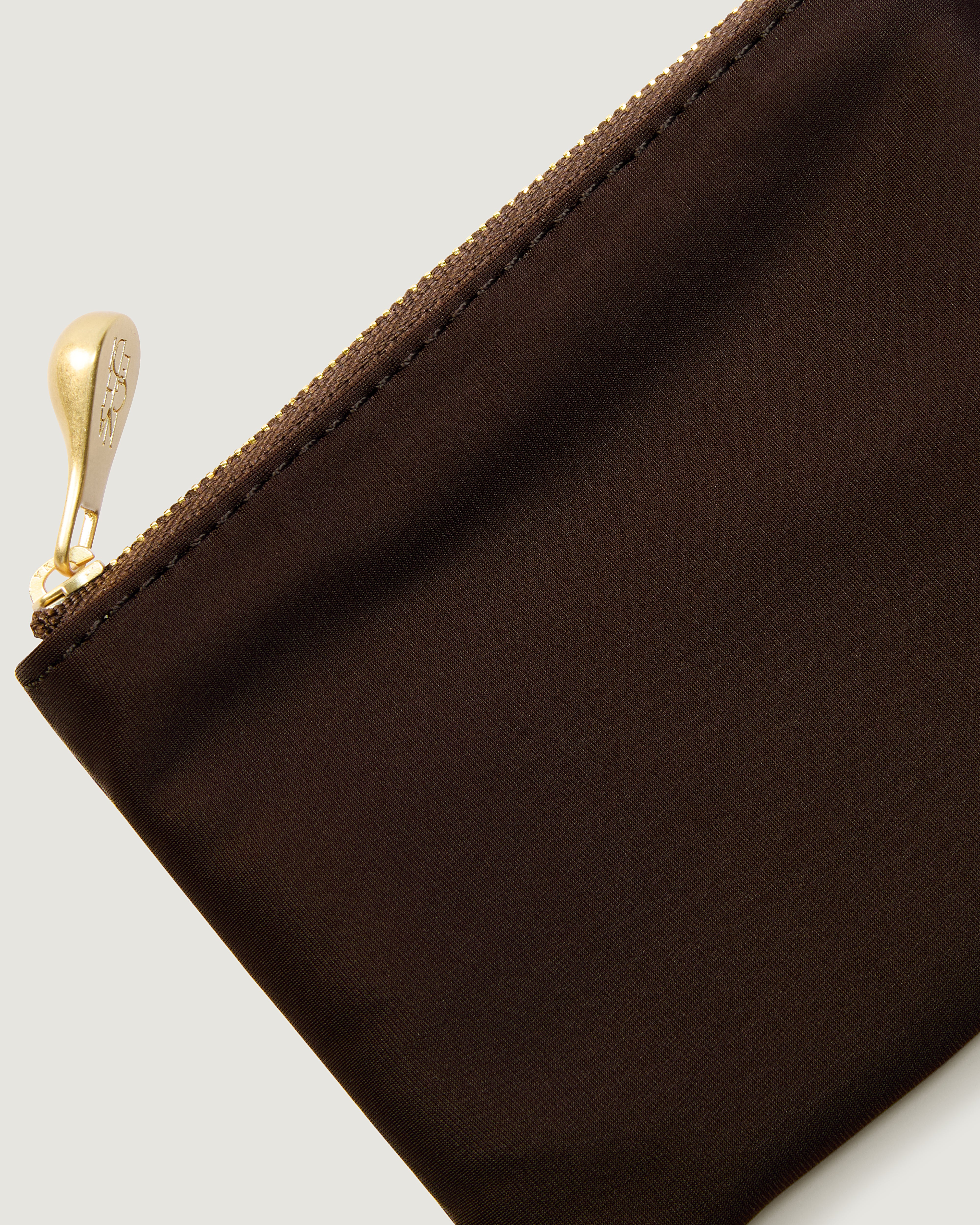 Close-up of a chocolate brown nylon pouch with a gold zipper pull