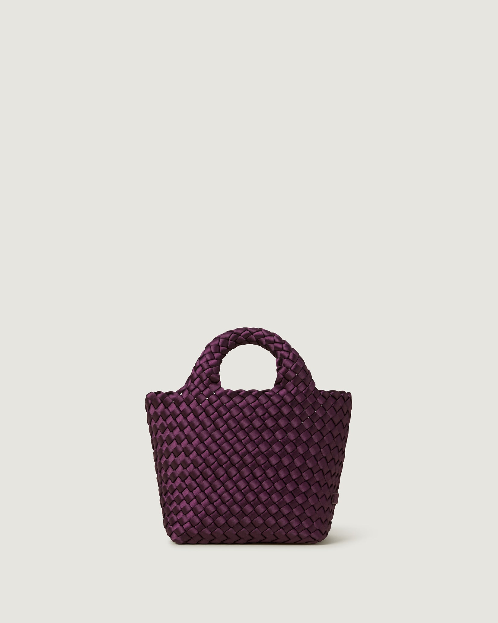 St. Barths Petit Satin Tote Bag in Currant, a deep purple tone, in handwoven neoprene featuring an open top, woven top handles, and detachable, adjustable nylon crossbody strap.