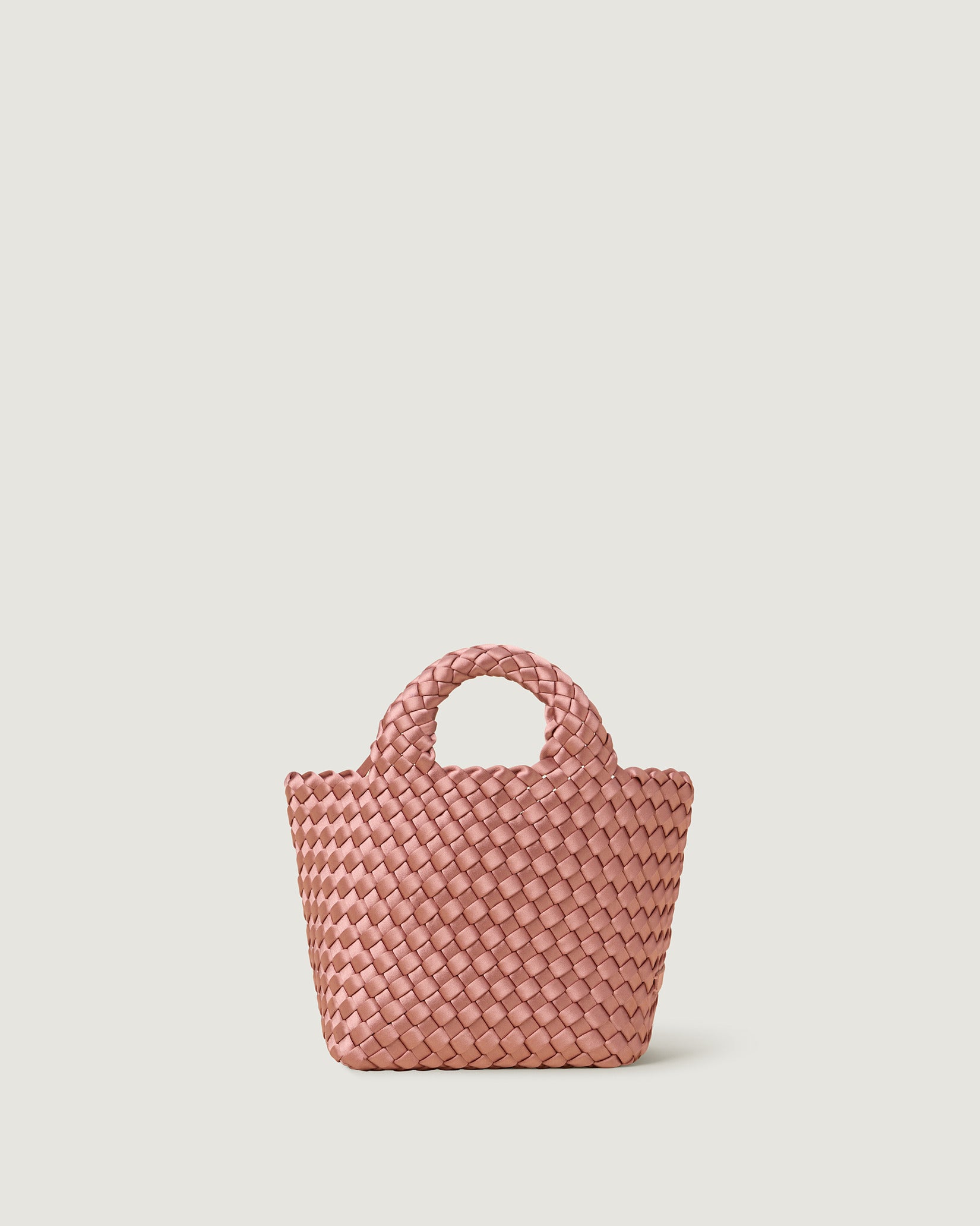 St. Barths Petit Satin Tote Bag in Daphne, a coral pink tone, in handwoven neoprene featuring an open top, woven top handles, and detachable, adjustable nylon crossbody strap.