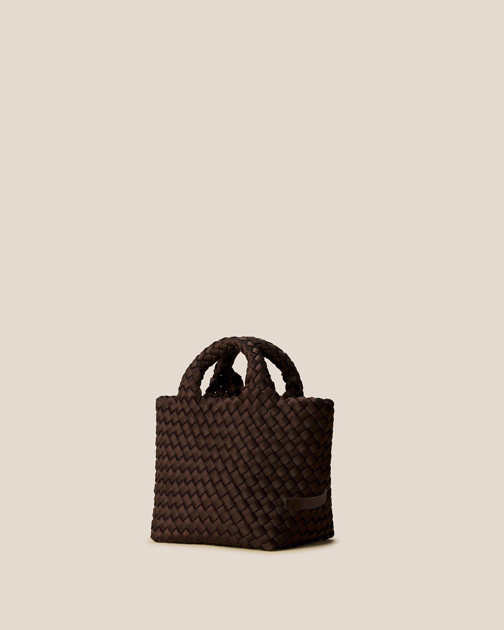 St. Barths Petit Tote Bag in Chocolate shown from a side angle, highlighting its handwoven neoprene and open top.