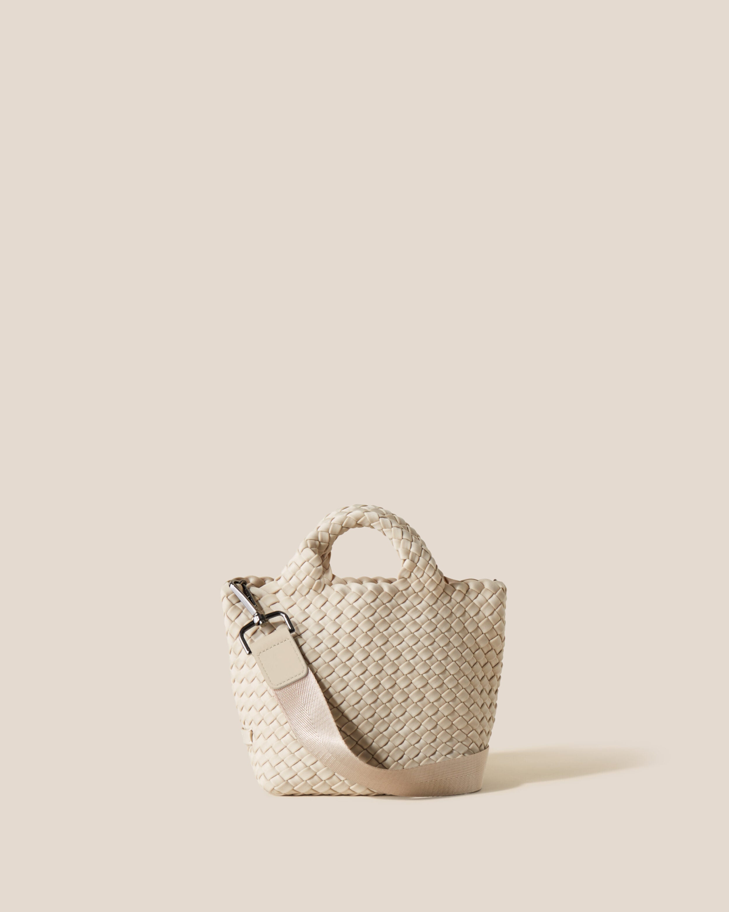 St. Barths Tote in Ecru, a cream tone, in handwoven neoprene, featuring an open top, woven top handles, and detachable, adjustable nylon crossbody strap.