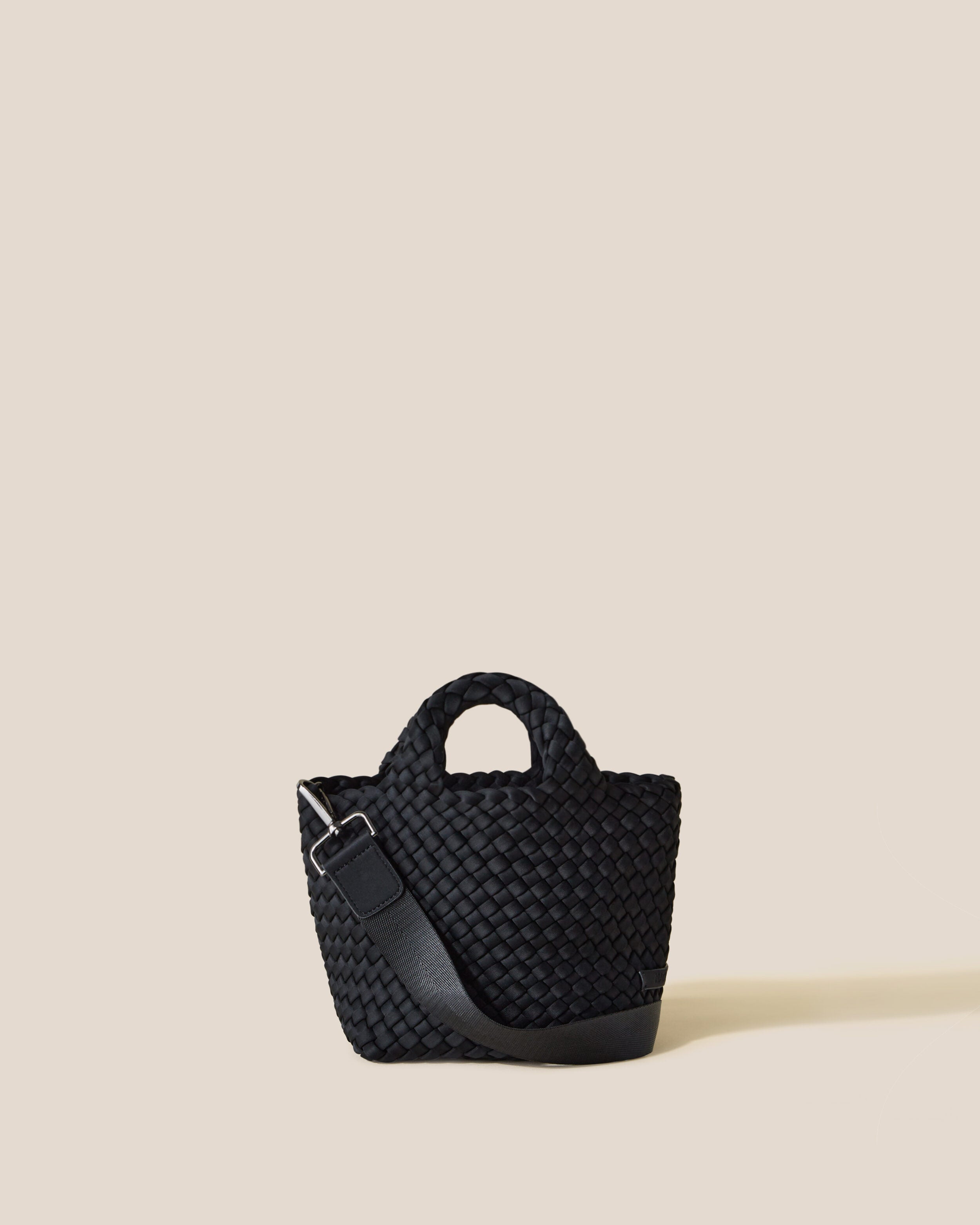 St. Barths Tote in Onyx, a true black tone, in handwoven neoprene, featuring an open top, woven top handles, and detachable, adjustable nylon crossbody strap.
