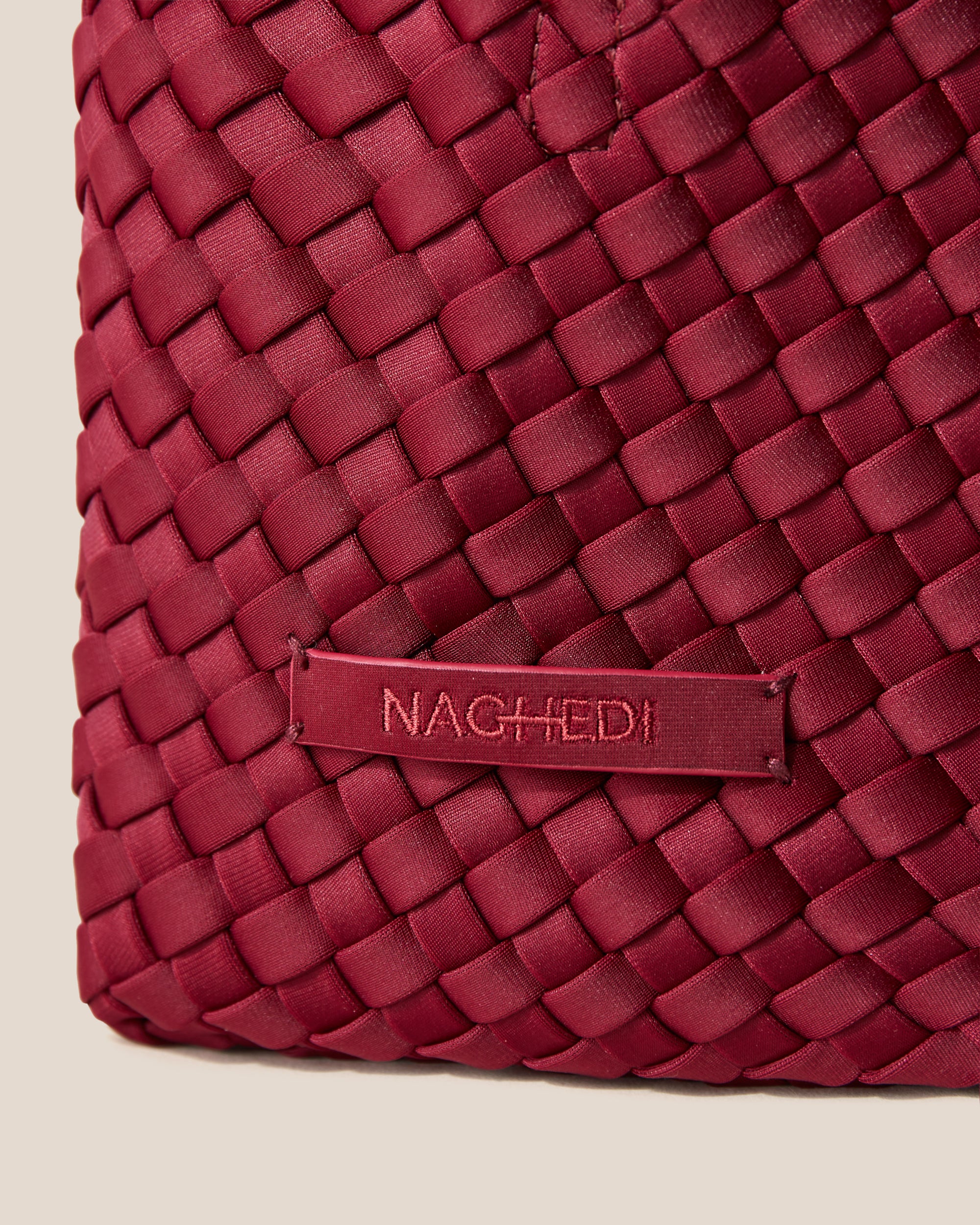 Close-up of stampled NAGHEDI logo and handwoven detailing on St. Barths Petit Tote Bag in Rosewood.