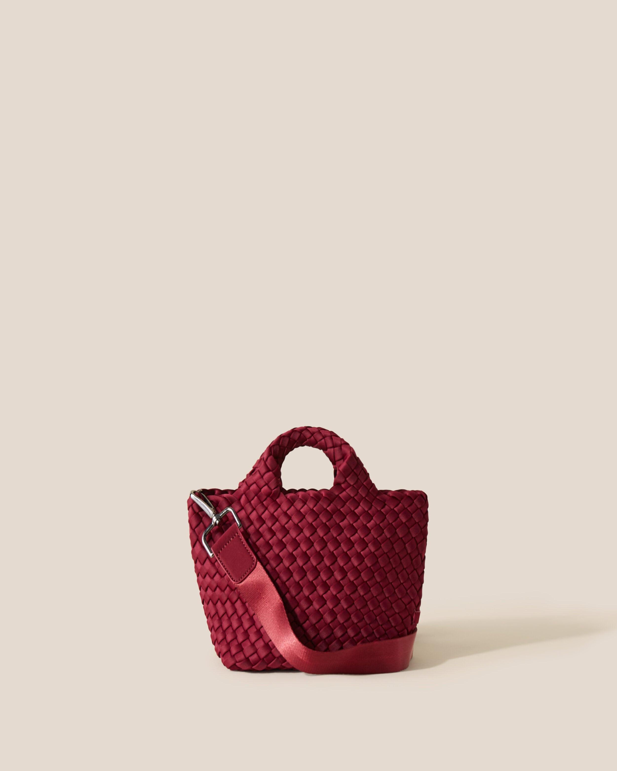 St. Barths Tote in Rosewood, a burgundy tone, in handwoven neoprene, featuring an open top, woven top handles, and detachable, adjustable nylon crossbody strap.