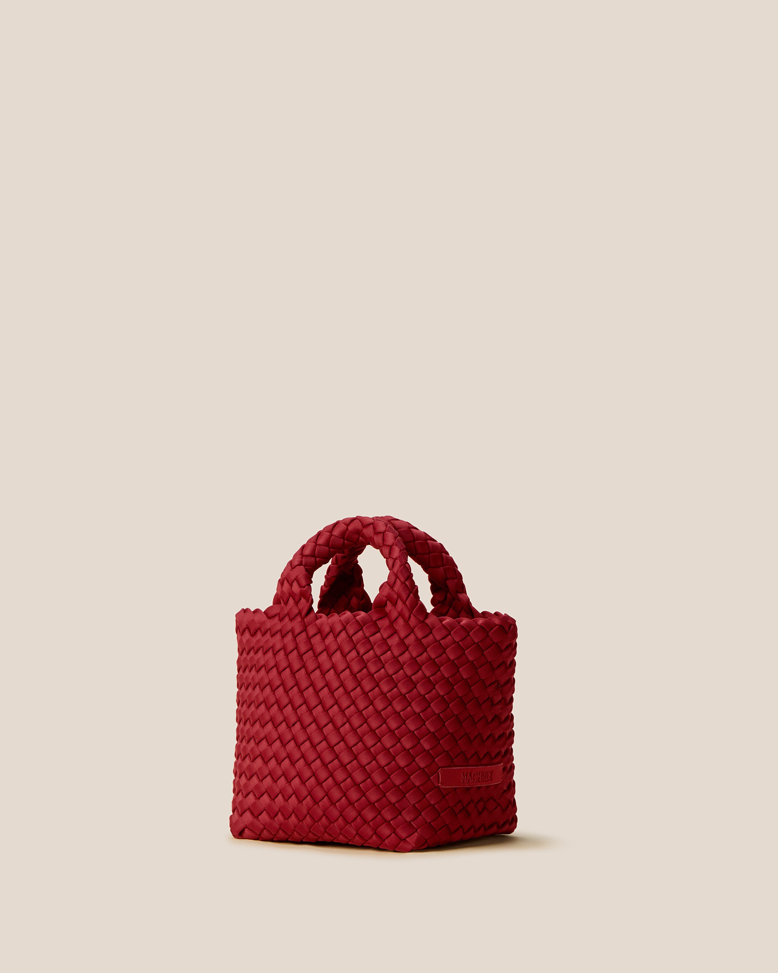 St. Barths Tote in Rosso shown from a side angle, highlighting its handwoven neoprene construction and open top.
