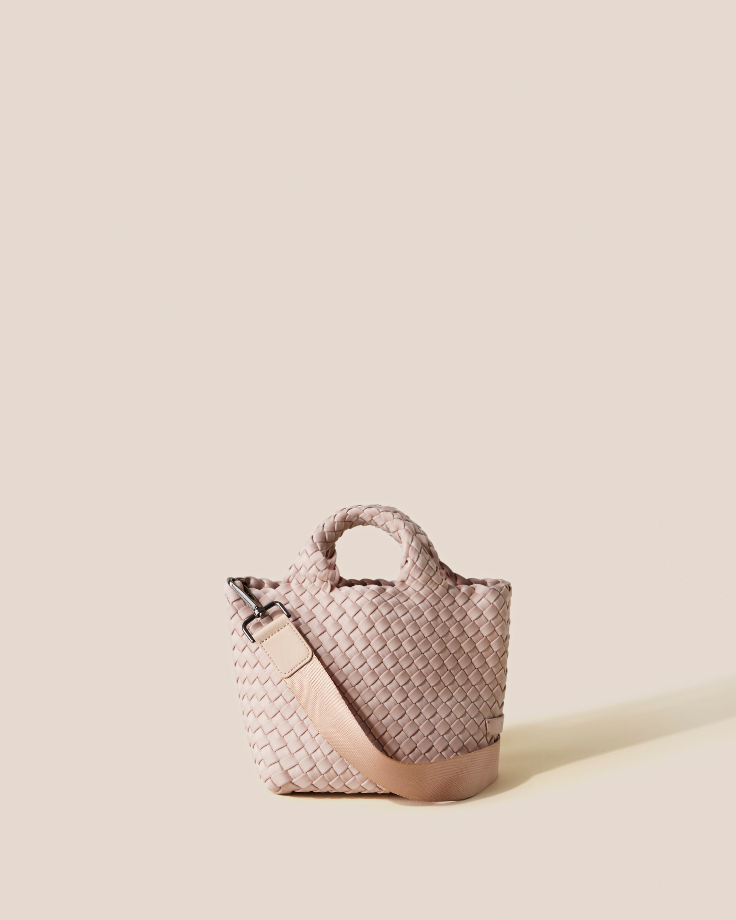 St. Barths Tote in Shell Pink, a soft ballet pink tone, in handwoven neoprene, featuring an open top, woven top handles, and detachable, adjustable nylon crossbody strap.