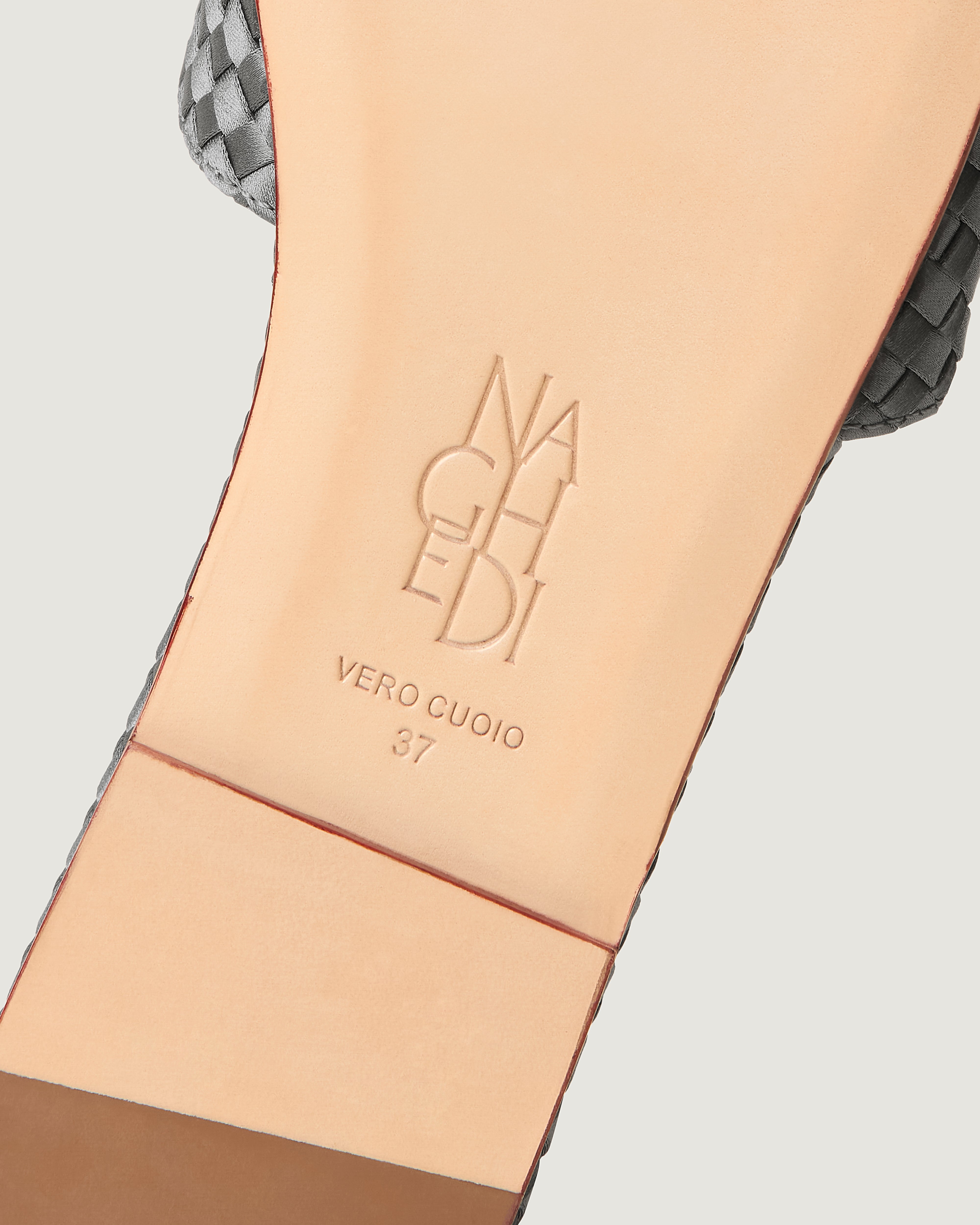Shoe sole showing natural buffed leather sole, stamped NAGHEDI logo and size detail for The St. Barths Slide in Graphite.