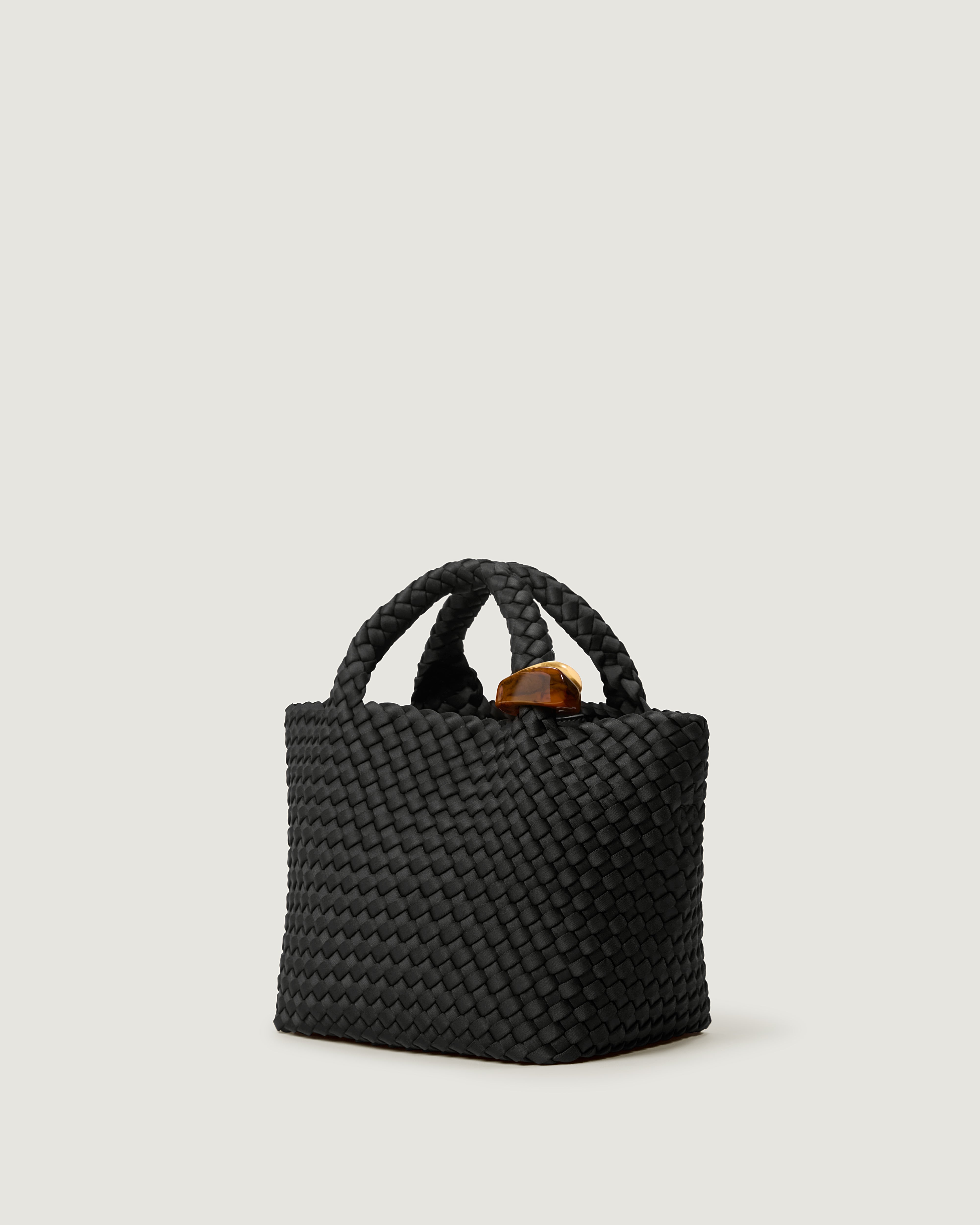 St. Barths Tote in Onyx shown from a side angle, highlighting its handwoven neoprene construction and open top.