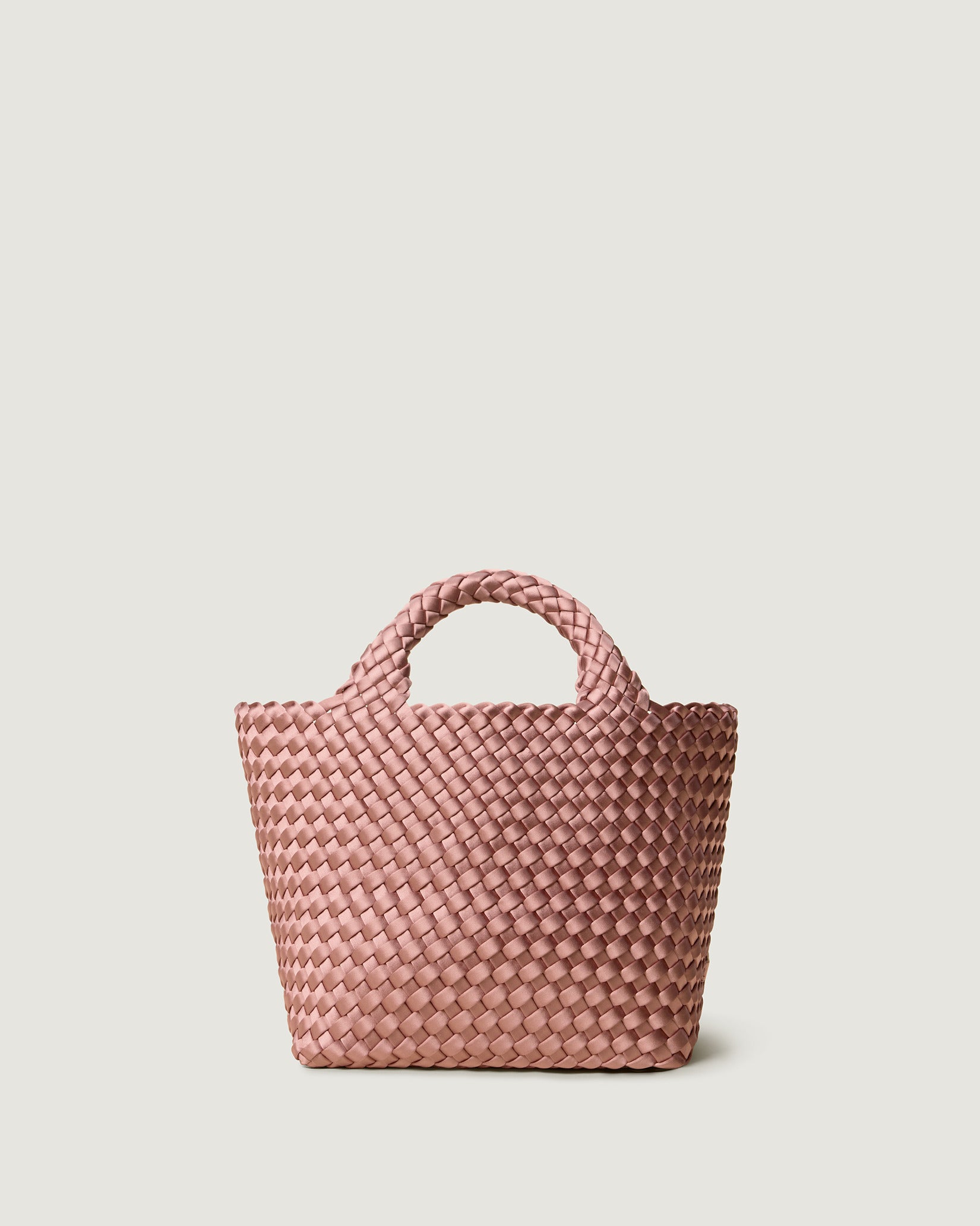 St. Barths Small Satin Tote Bag in Daphne, a coral pink tone, in handwoven neoprene featuring an open top, woven top handles, and detachable, adjustable nylon crossbody strap.