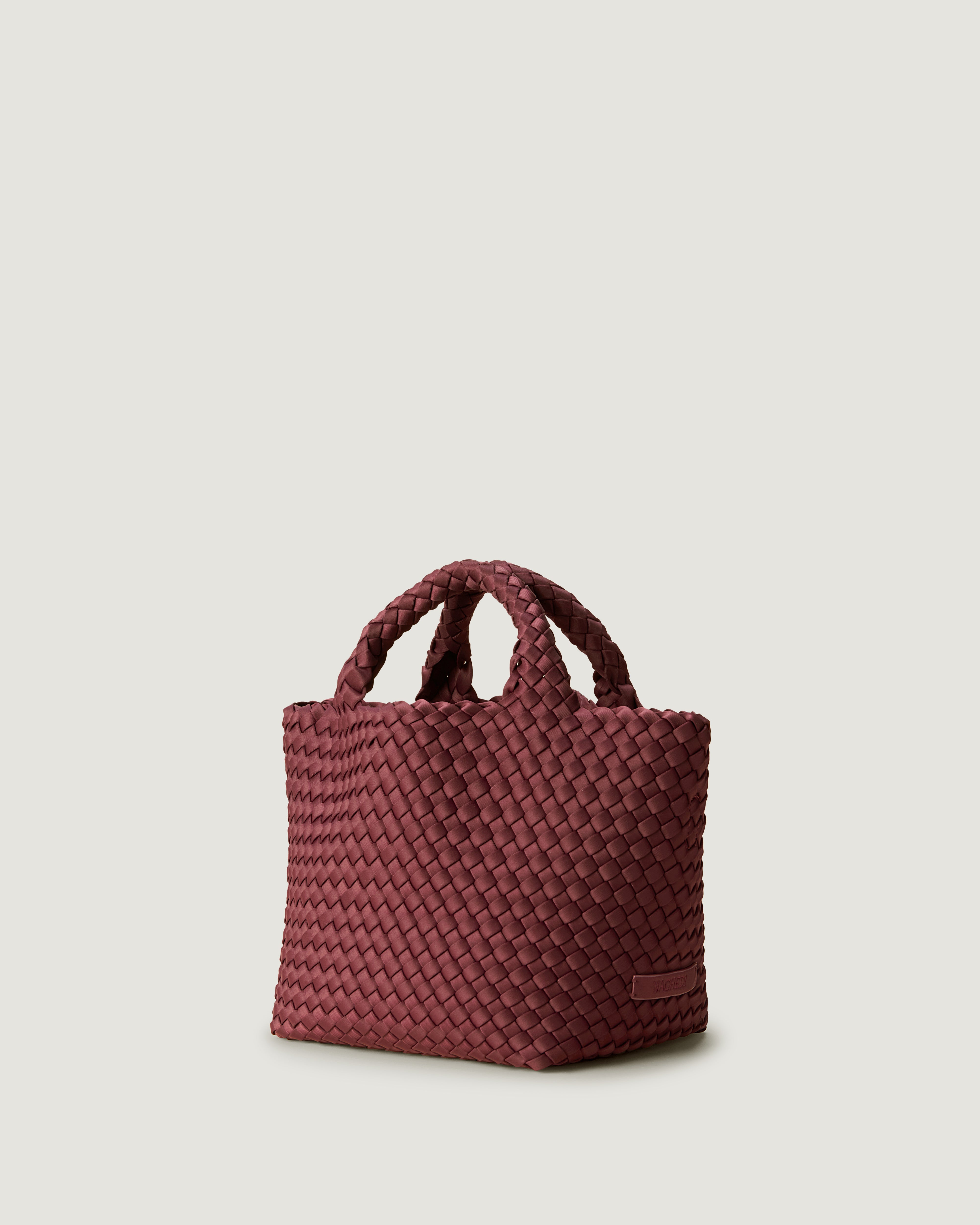 Side view of St. Barths Tote in Bordeaux, handwoven in burgundy neoprene. Featuring an open top, and woven top handles.