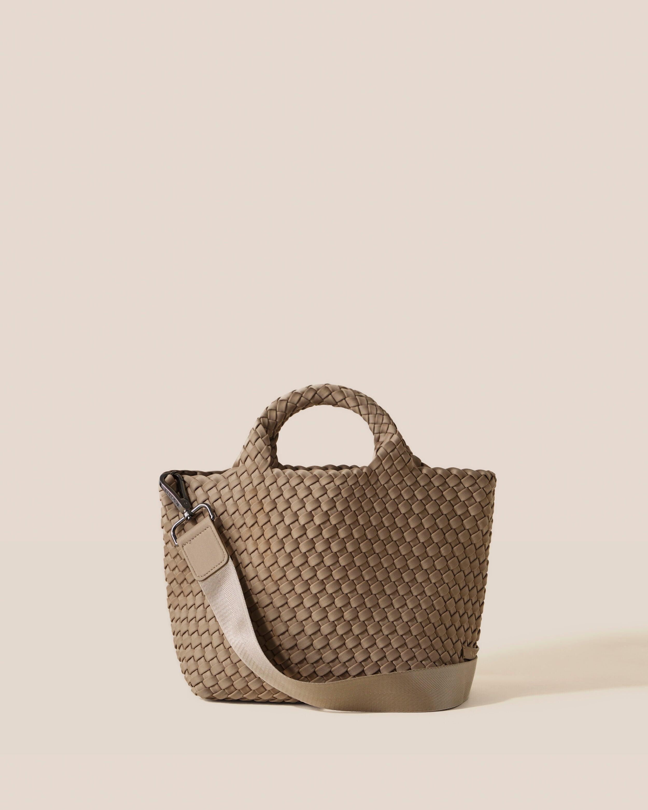 St. Barths Tote in Cashmere, a taupe tone, in handwoven neoprene, featuring an open top, woven top handles, and detachable, adjustable nylon crossbody strap.