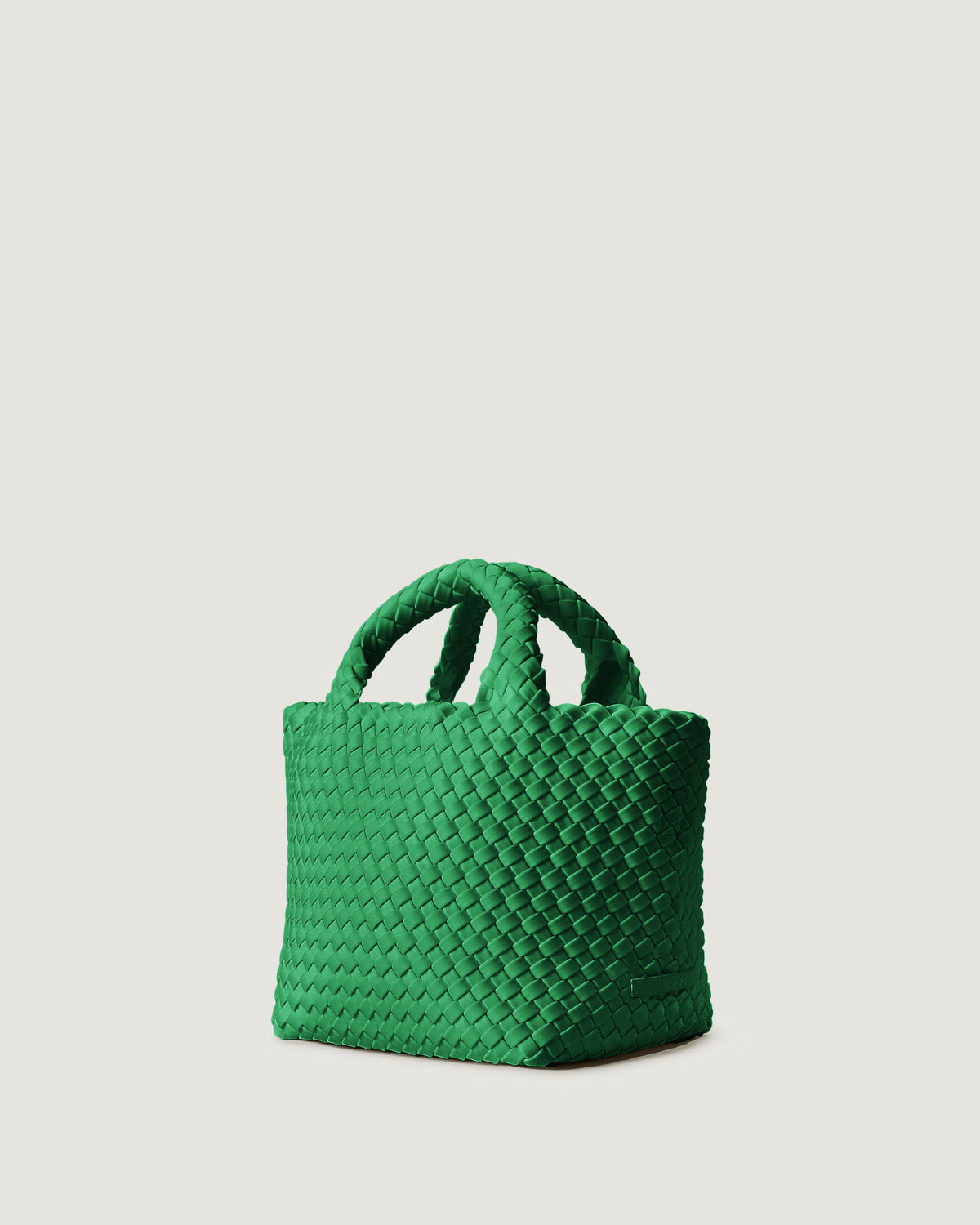 St. Barths Tote in Emerald shown from a side angle, highlighting its handwoven neoprene construction and open top with magnetic snap closure.