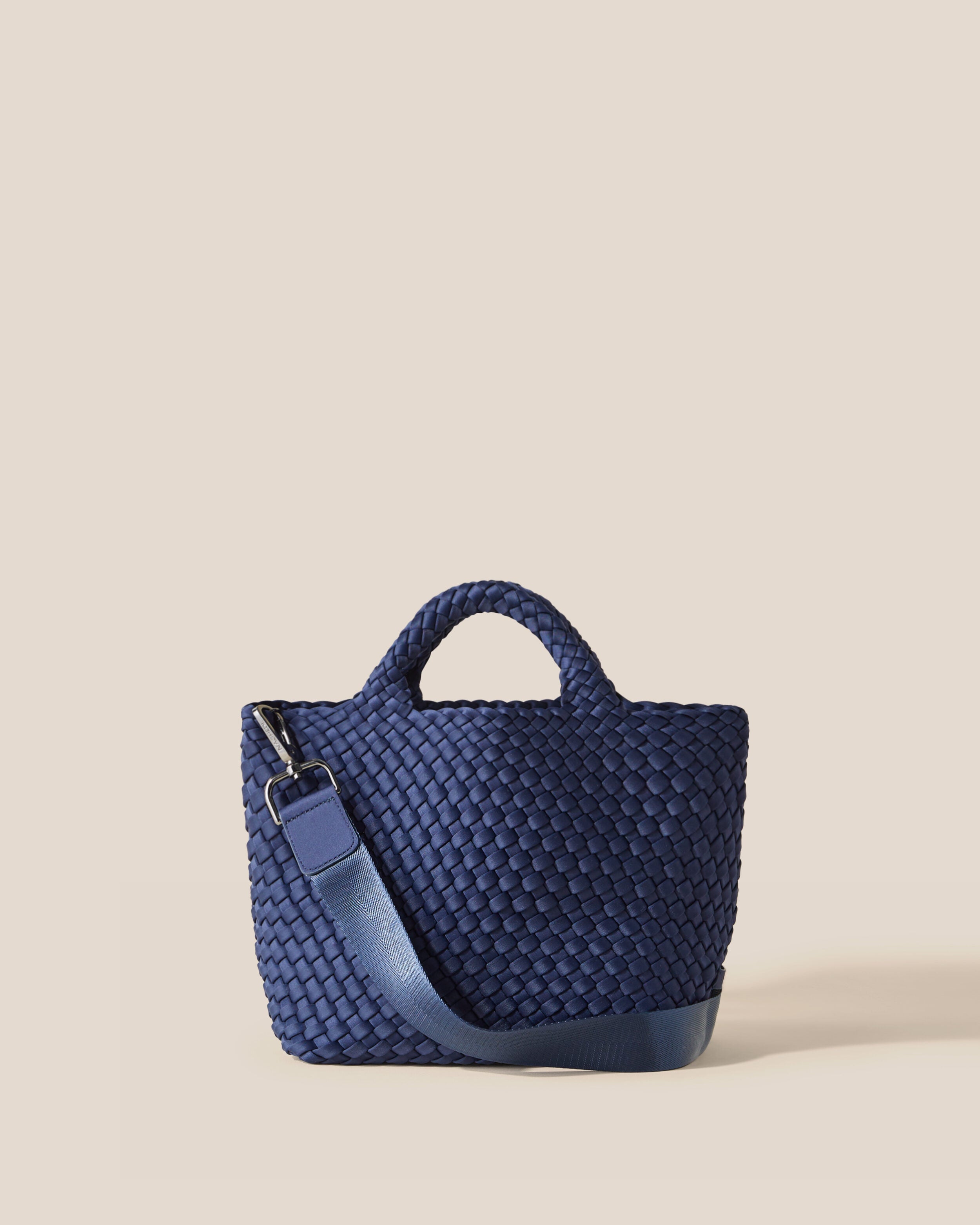 St. Barths Tote in Ink Blue, a navy blue tone, in handwoven neoprene, featuring an open top, woven top handles, and detachable, adjustable nylon crossbody strap.