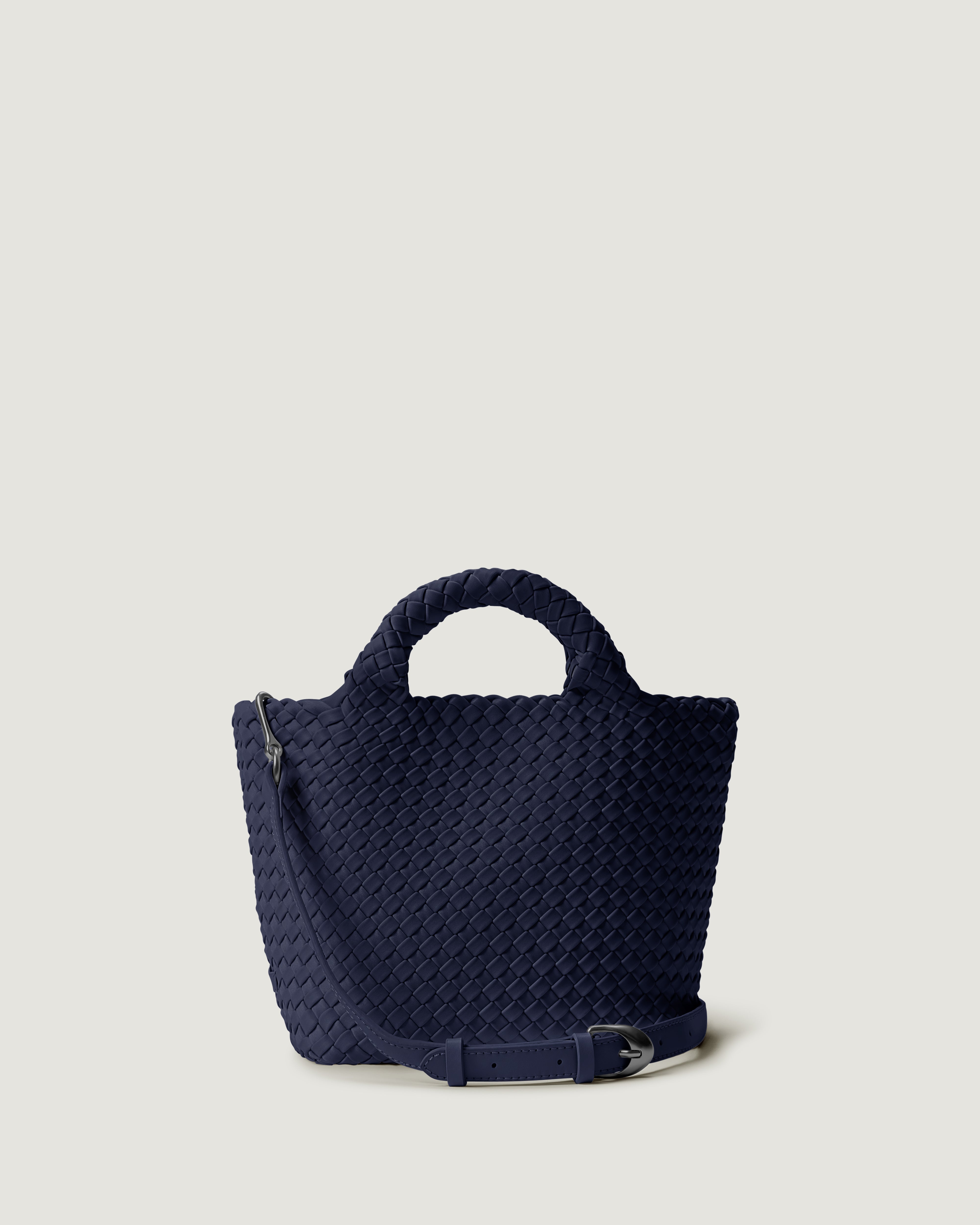 St. Barths Tote in Ink Blue, a navy blue tone, in handwoven neoprene, featuring an magnetic closure, woven top handles, and detachable, adjustable leather crossbody strap.