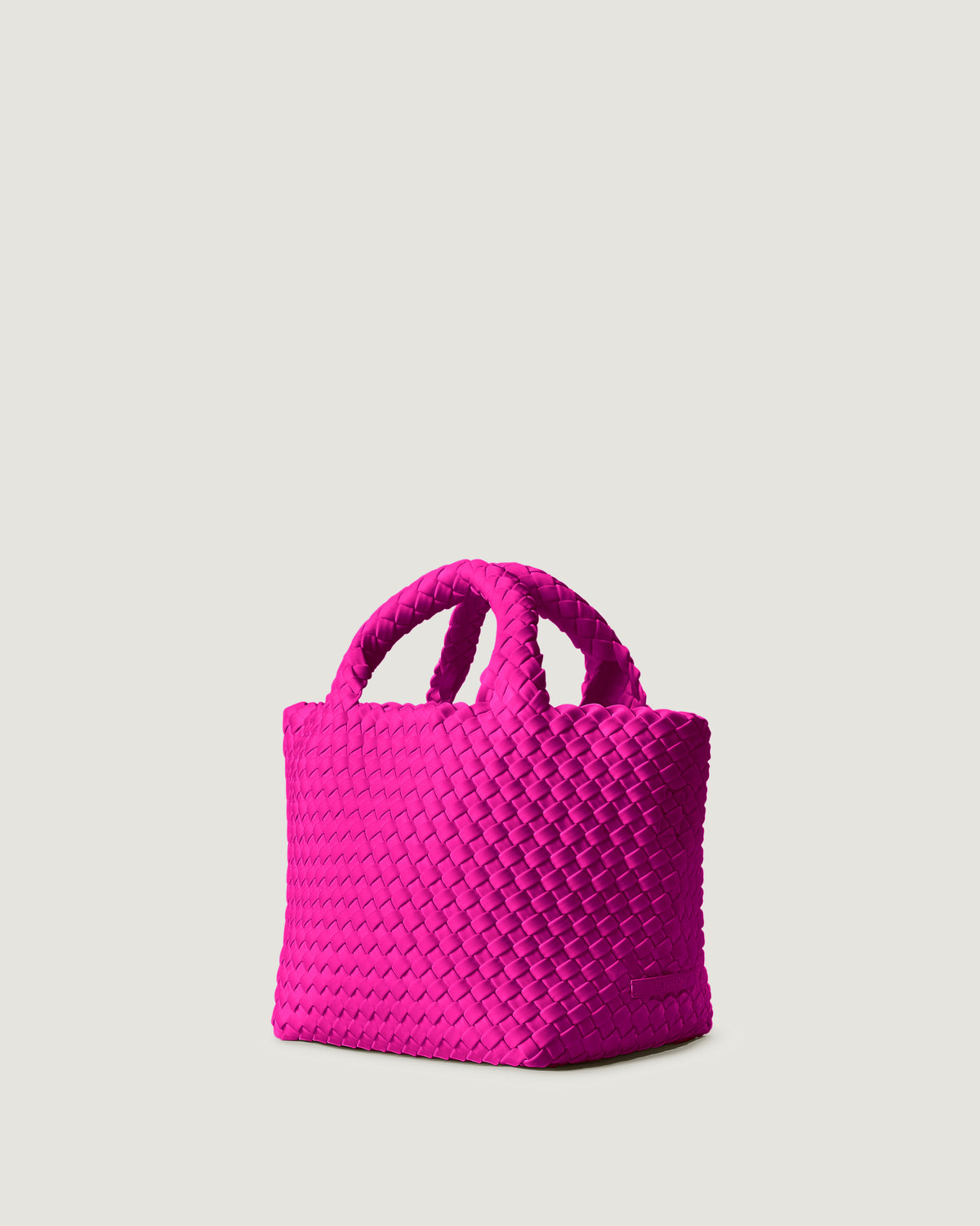 St. Barths Tote in Miami Pink shown from a side angle, highlighting its handwoven neoprene construction and open top with magnetic snap closure.