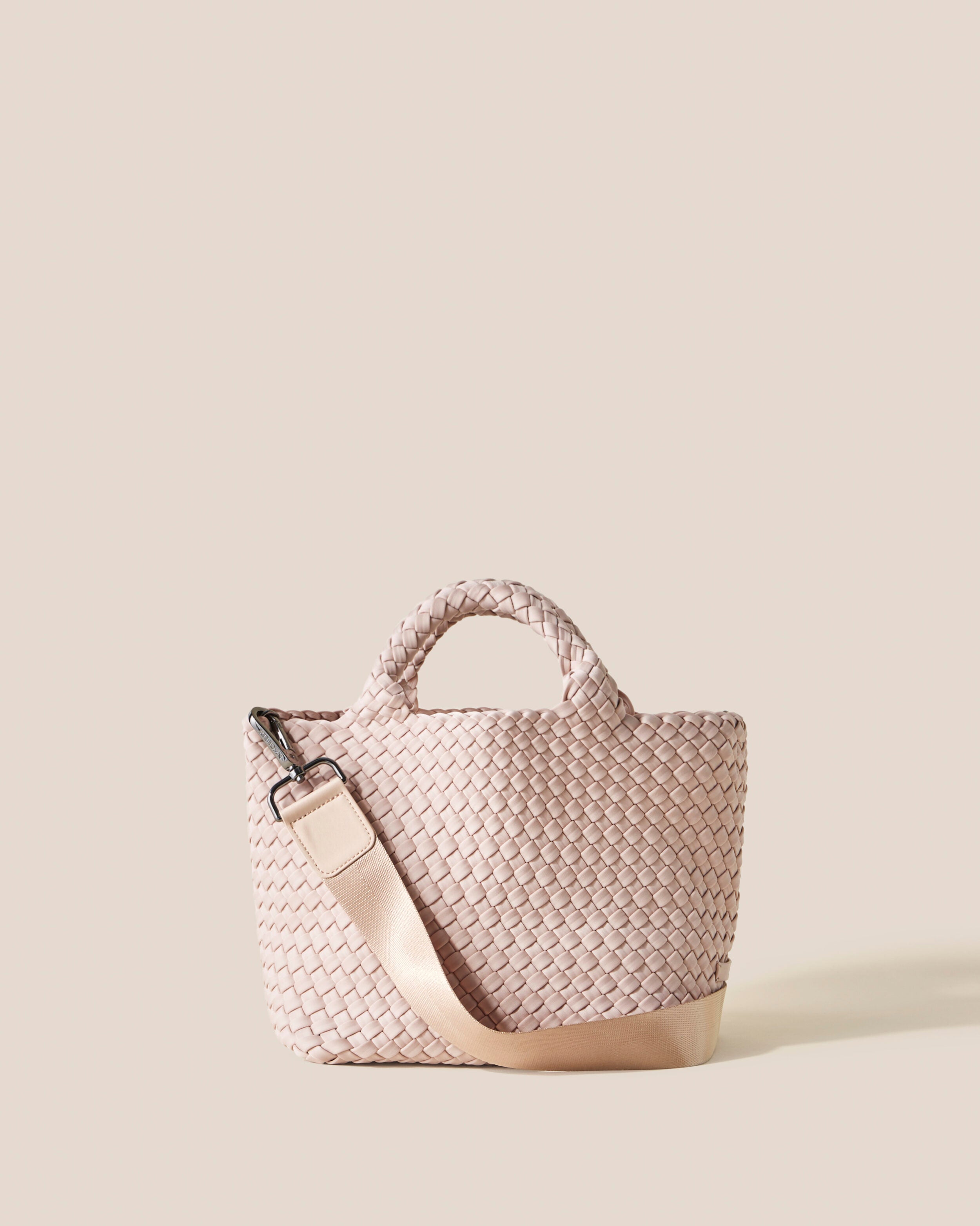 St. Barths Tote in Shell Pink, a soft ballet pink tone, in handwoven neoprene, featuring an open top, woven top handles, and detachable, adjustable nylon crossbody strap.