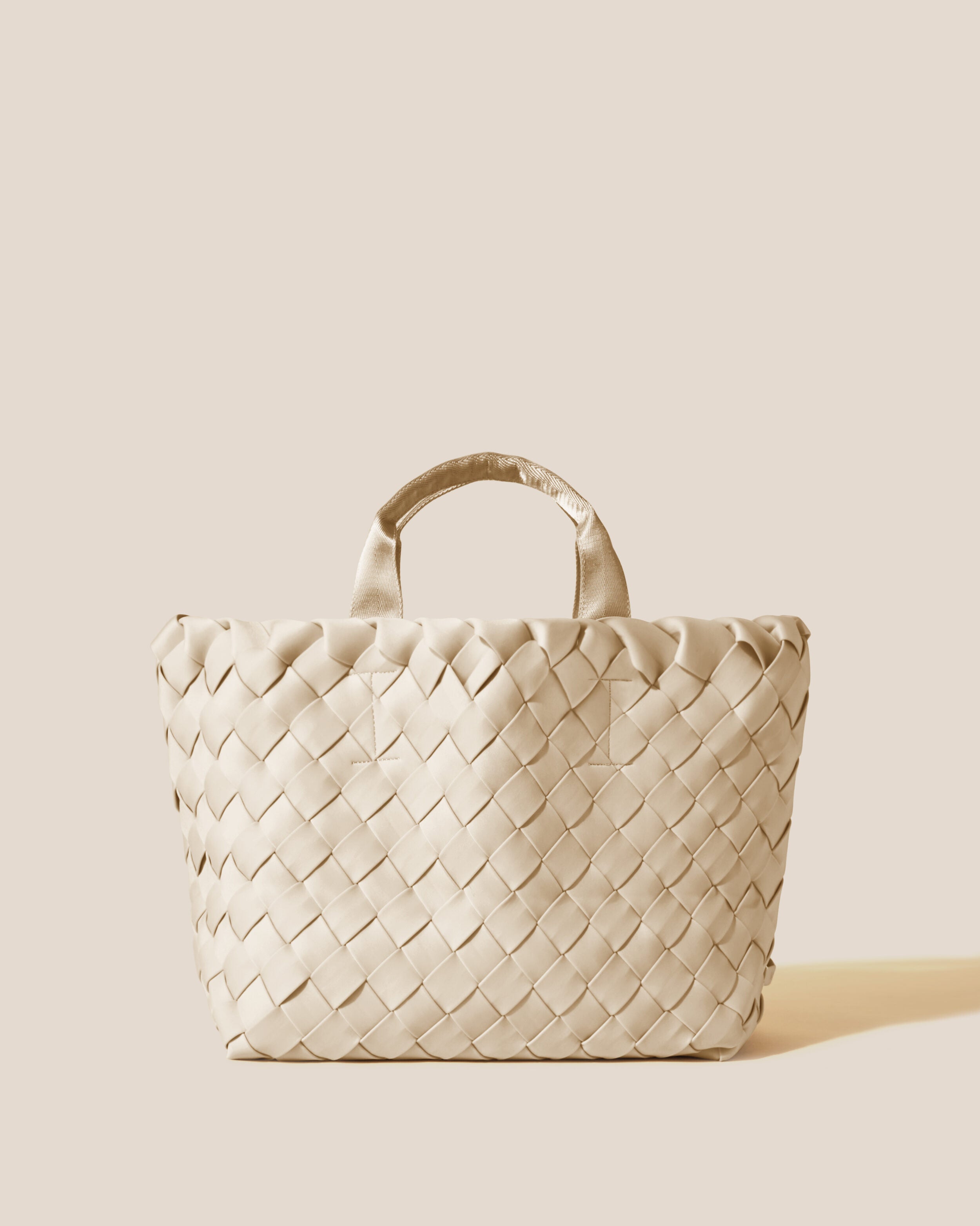 Tangier Tote in Ecru, a cream tone, in handwoven neoprene, featuring an open top, and sleek nylon webbing handles.