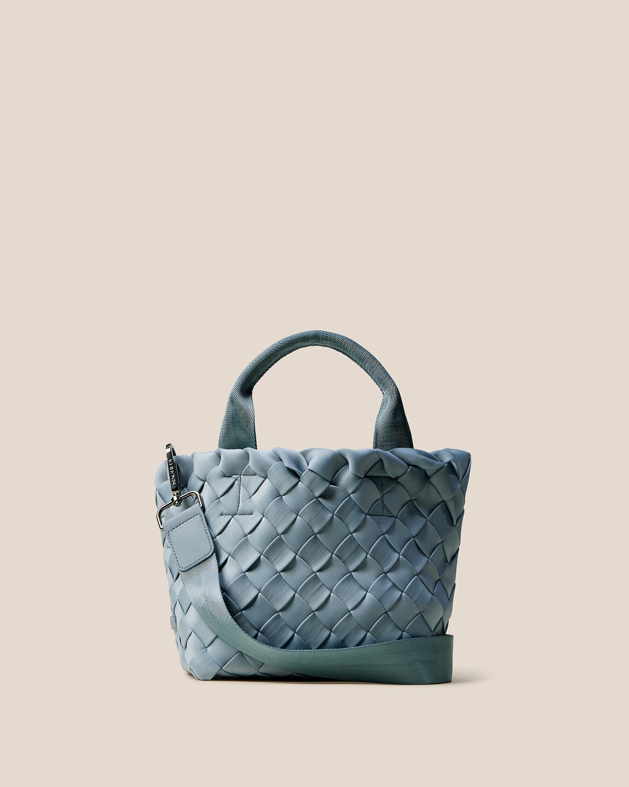 Tangier Tote in Nova, a muted denim blue tone, in handwoven neoprene, featuring an open top, sleek nylon webbing handles, and detachable, adjustable nylon crossbody strap.