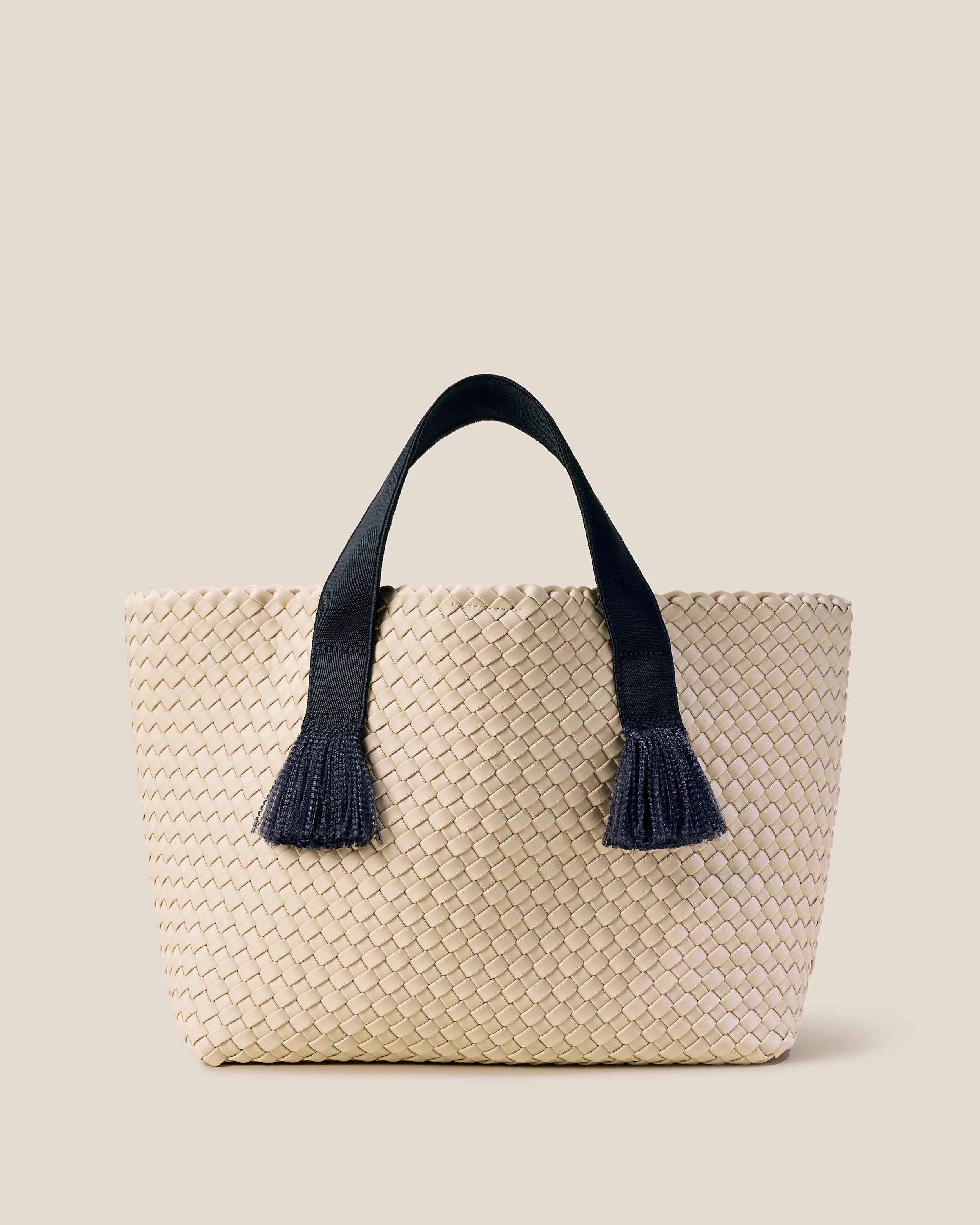 Tulum Tote in Moon, a cream with nylon handles in true black tone, in handwoven neoprene, featuring an open top with magnetic snap closure, and sleek nylon webbing handles with frayed detail fit over the shoulder.