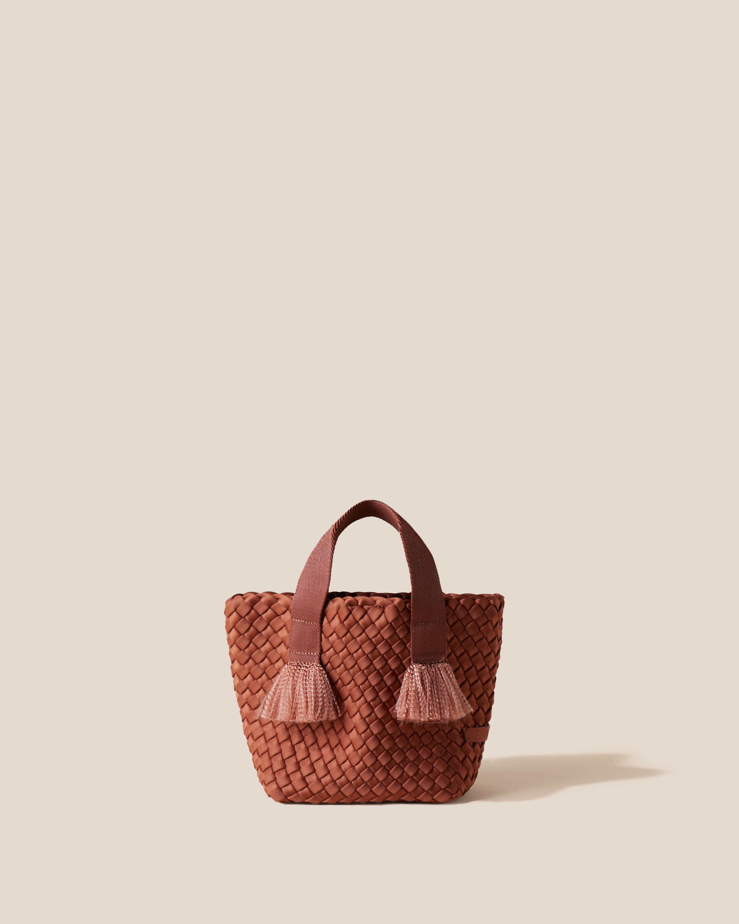 Tulum Tote in Adobe, a clay brown tone, in handwoven neoprene, featuring an open top with magnetic snap closure, nylon handles with frayed detail, and detachable, adjustable nylon crossbody strap.