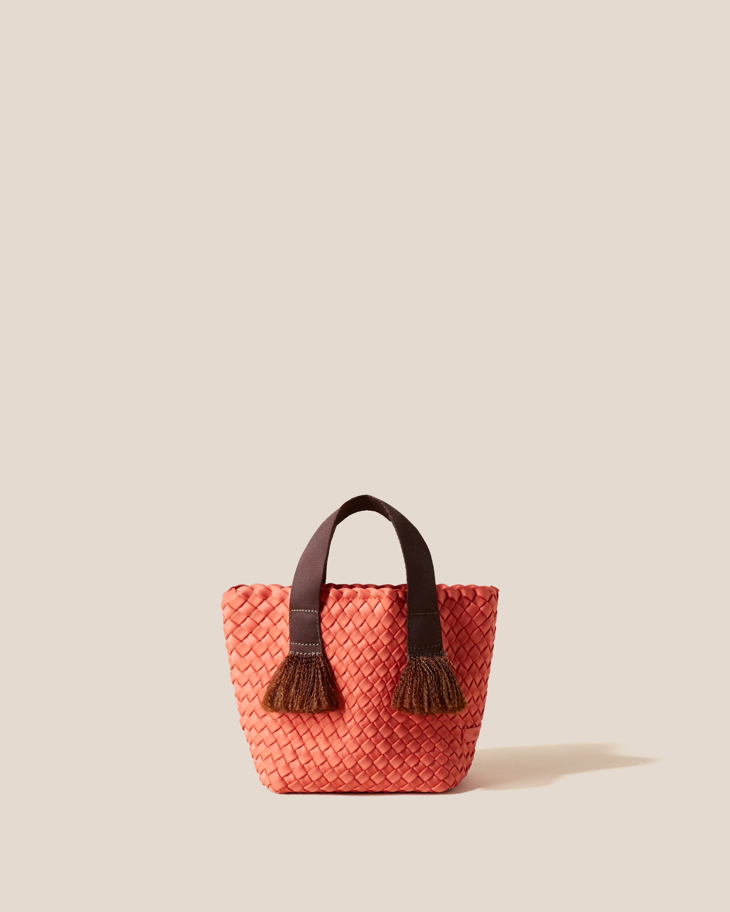Tulum Tote in Bonaire, a muted orange tone, in handwoven neoprene, featuring an open top with magnetic snap closure, nylon handles with frayed detail, and detachable, adjustable nylon crossbody strap.
