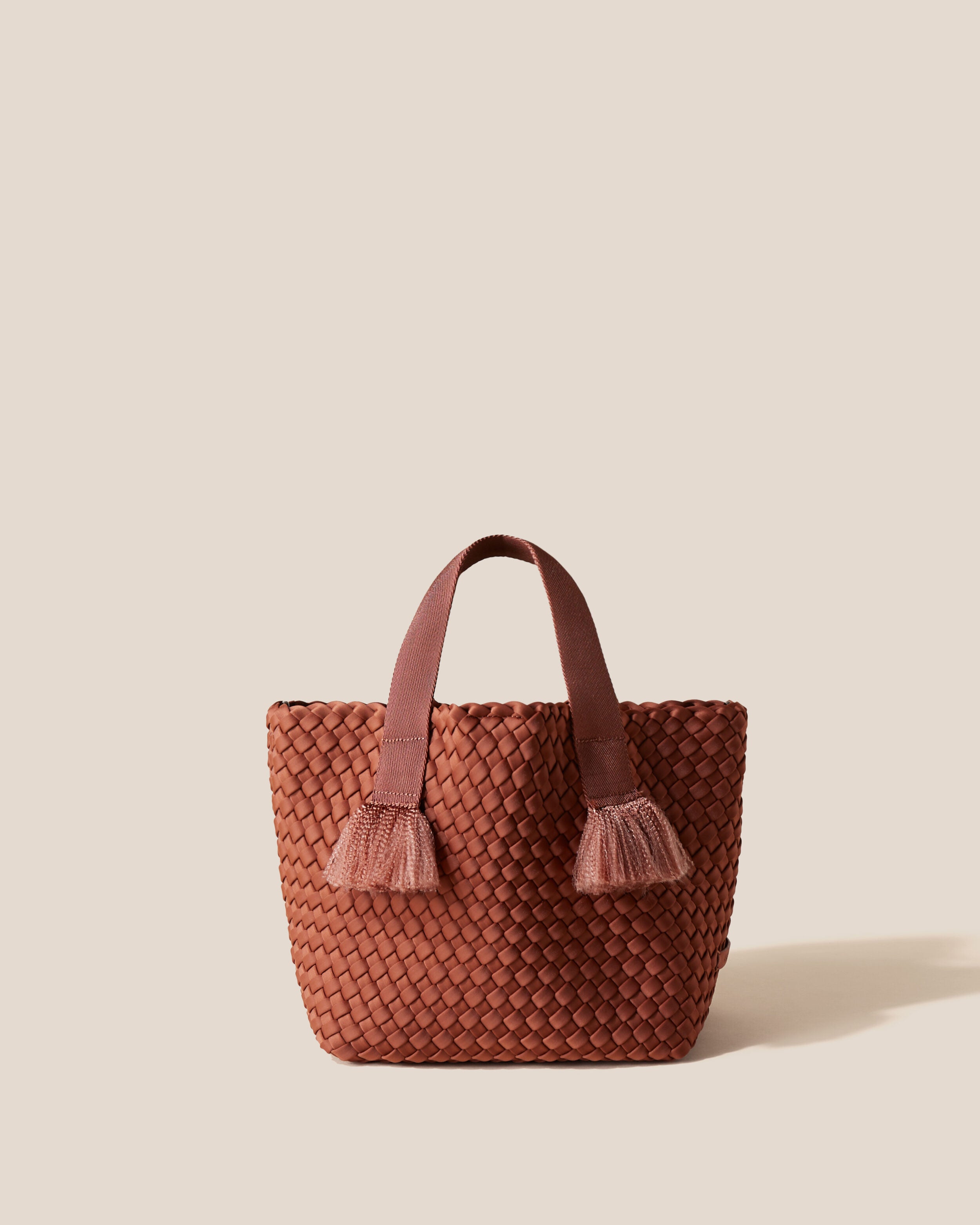 Tulum Tote in Adobe, a clay brown tone, in handwoven neoprene, featuring an open top with magnetic snap closure, nylon handles with frayed detail, and detachable, adjustable nylon crossbody strap.
