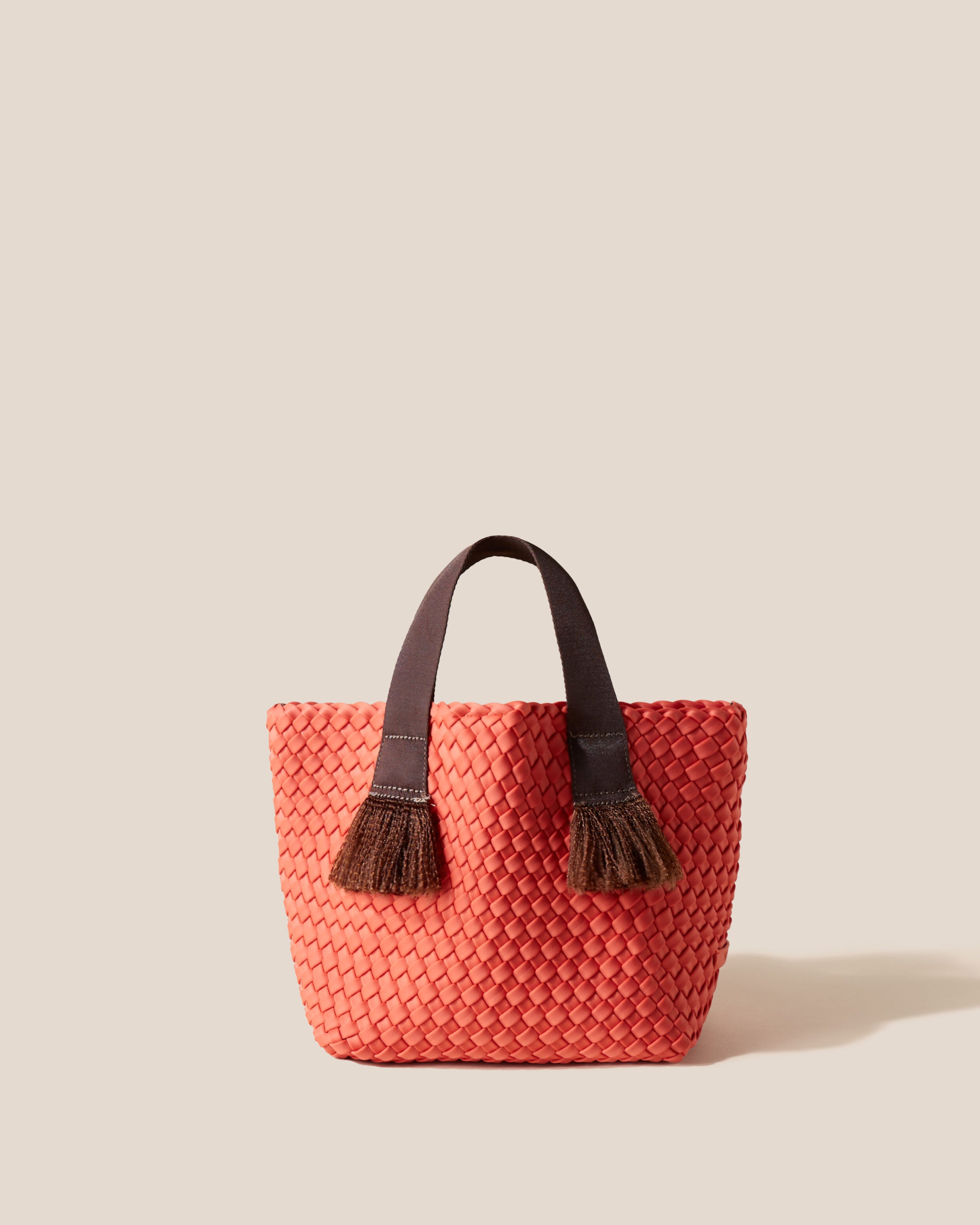 Tulum Tote in Bonaire, a muted orange tone, in handwoven neoprene, featuring an open top with magnetic snap closure, nylon handles with frayed detail, and detachable, adjustable nylon crossbody strap.