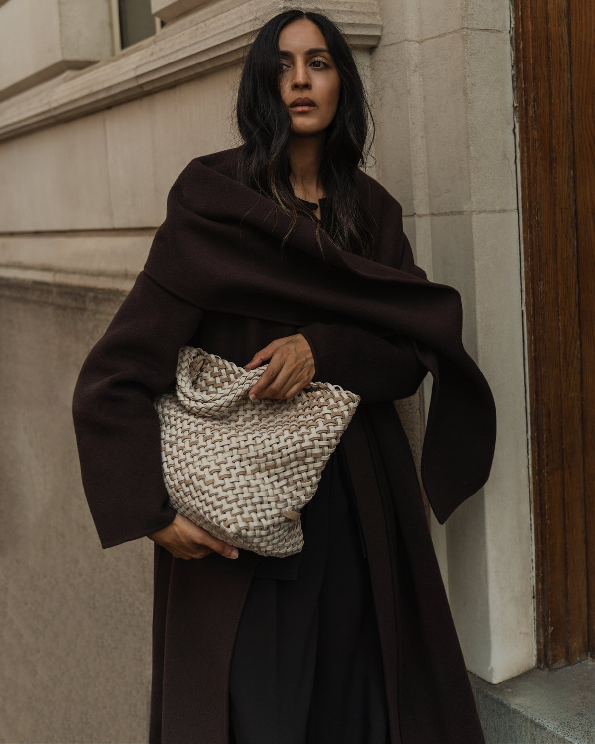 Woman holding St. Barths Medium tote in handwoven neoprene and suede in ivory color at her side. Soft silhouette and relaxed structure of bag are shown