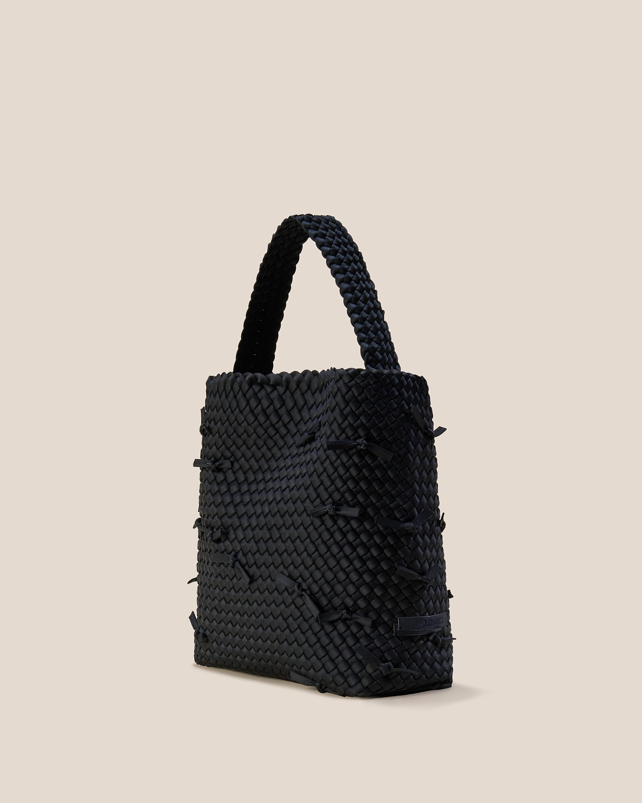 St. Barths Tote in Onyx shown from a side angle, highlighting its handwoven neoprene construction and open top with magnetic snap closure.