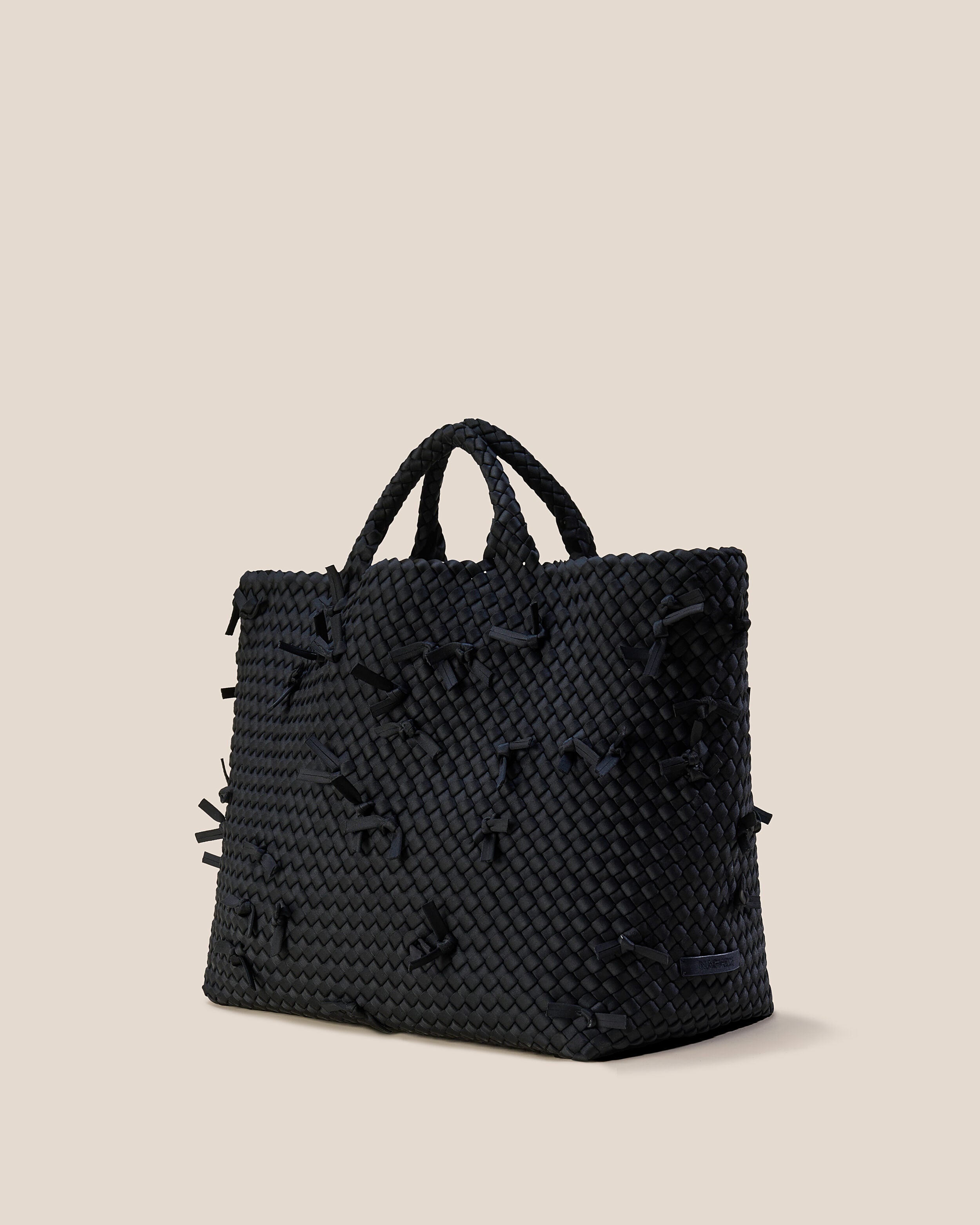 St. Barths Tote in Onyx shown from a side angle, highlighting its handwoven neoprene construction and open top.