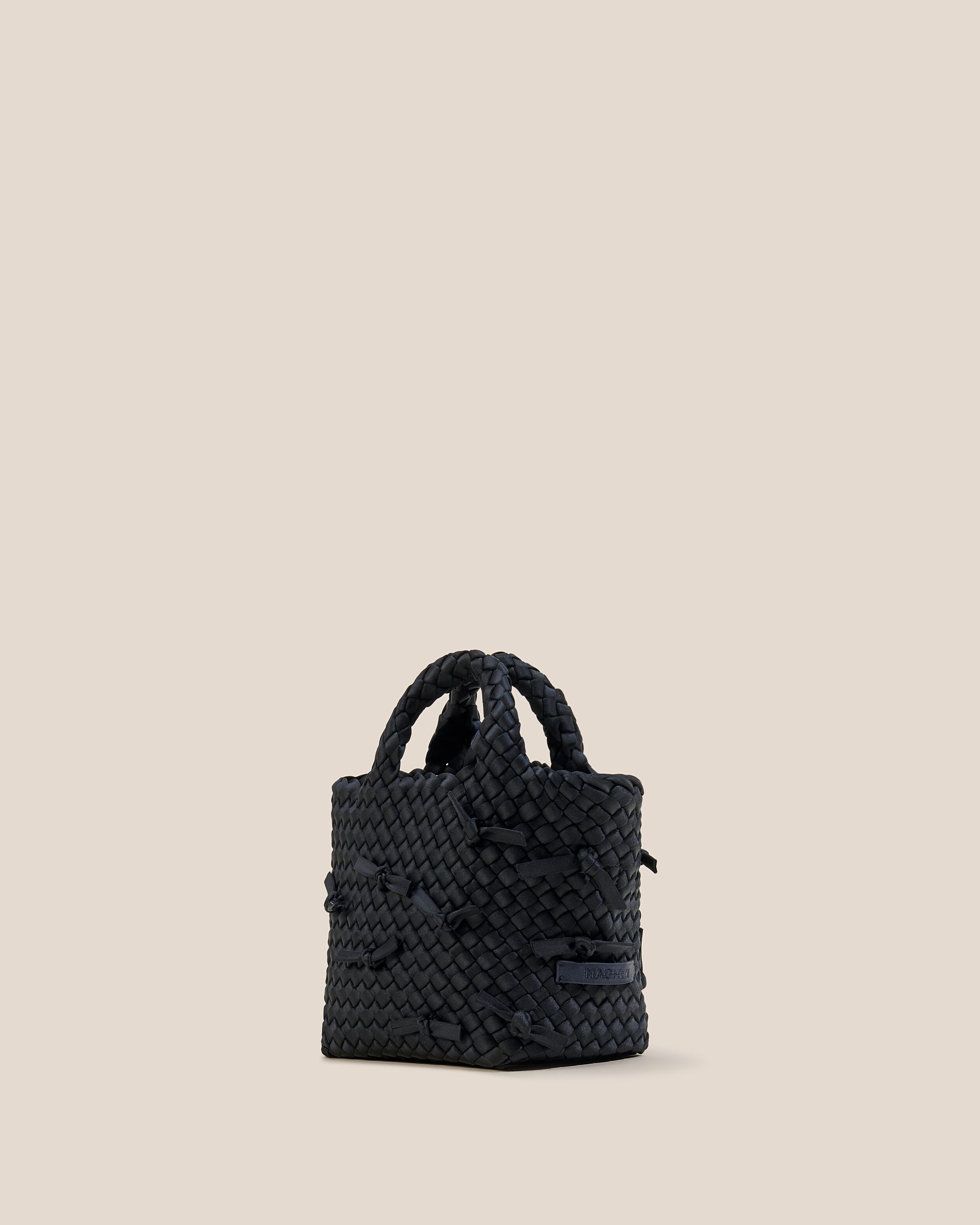 St. Barths Tote in Onyx shown from a side angle, highlighting its handwoven neoprene construction and open top.