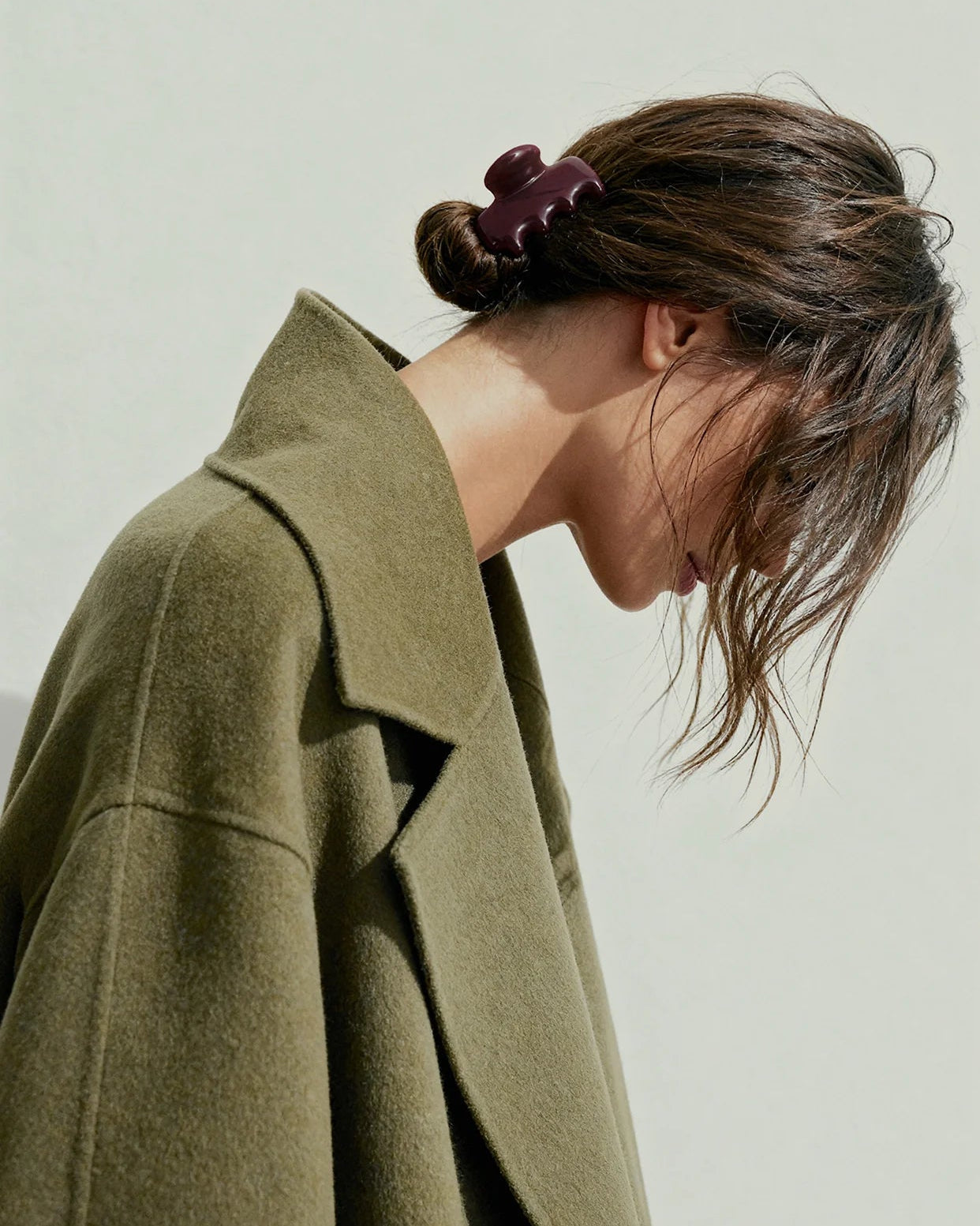 Woman wearing a maroon plastic hair clip and green coat